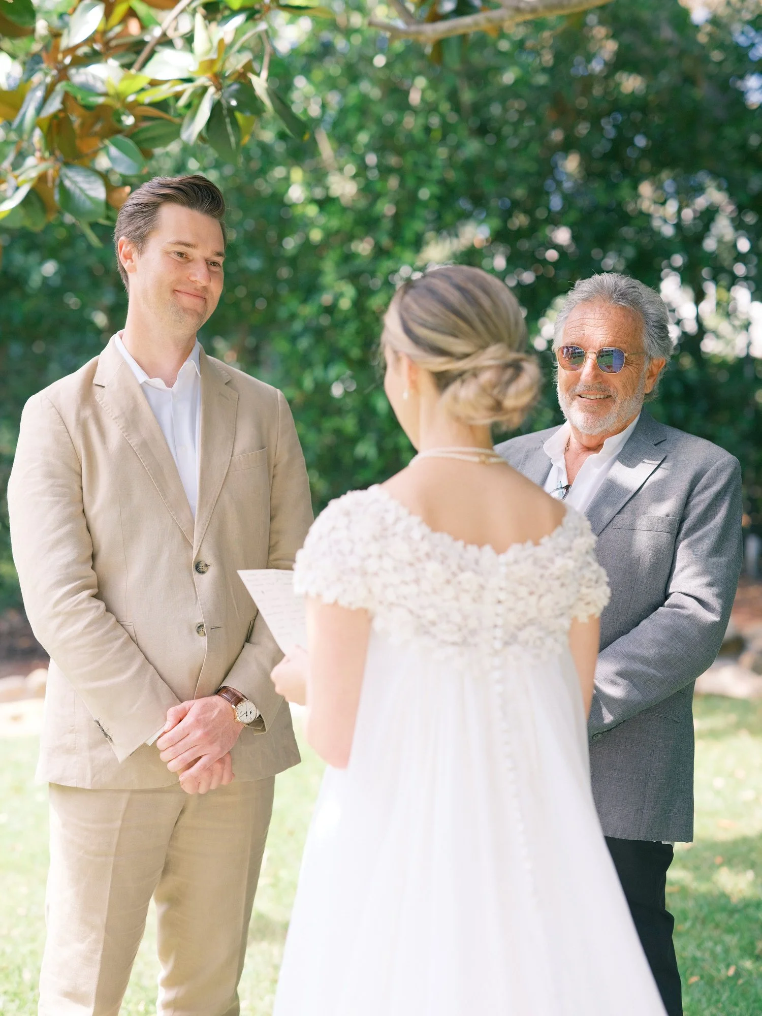 Bride and groom holding hands and smiling during their outdoor ceremony.