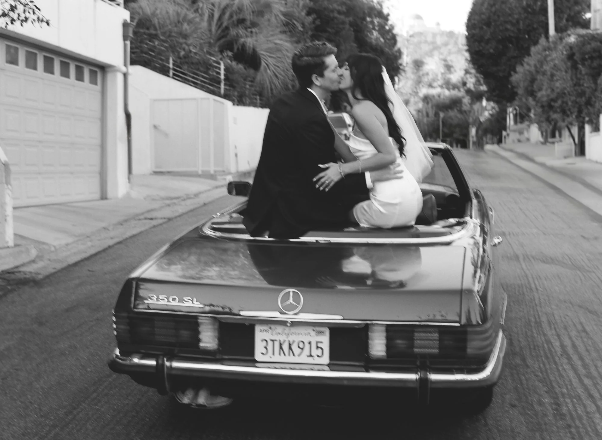 Black and white photo of couple sitting in a vintage convertible car.