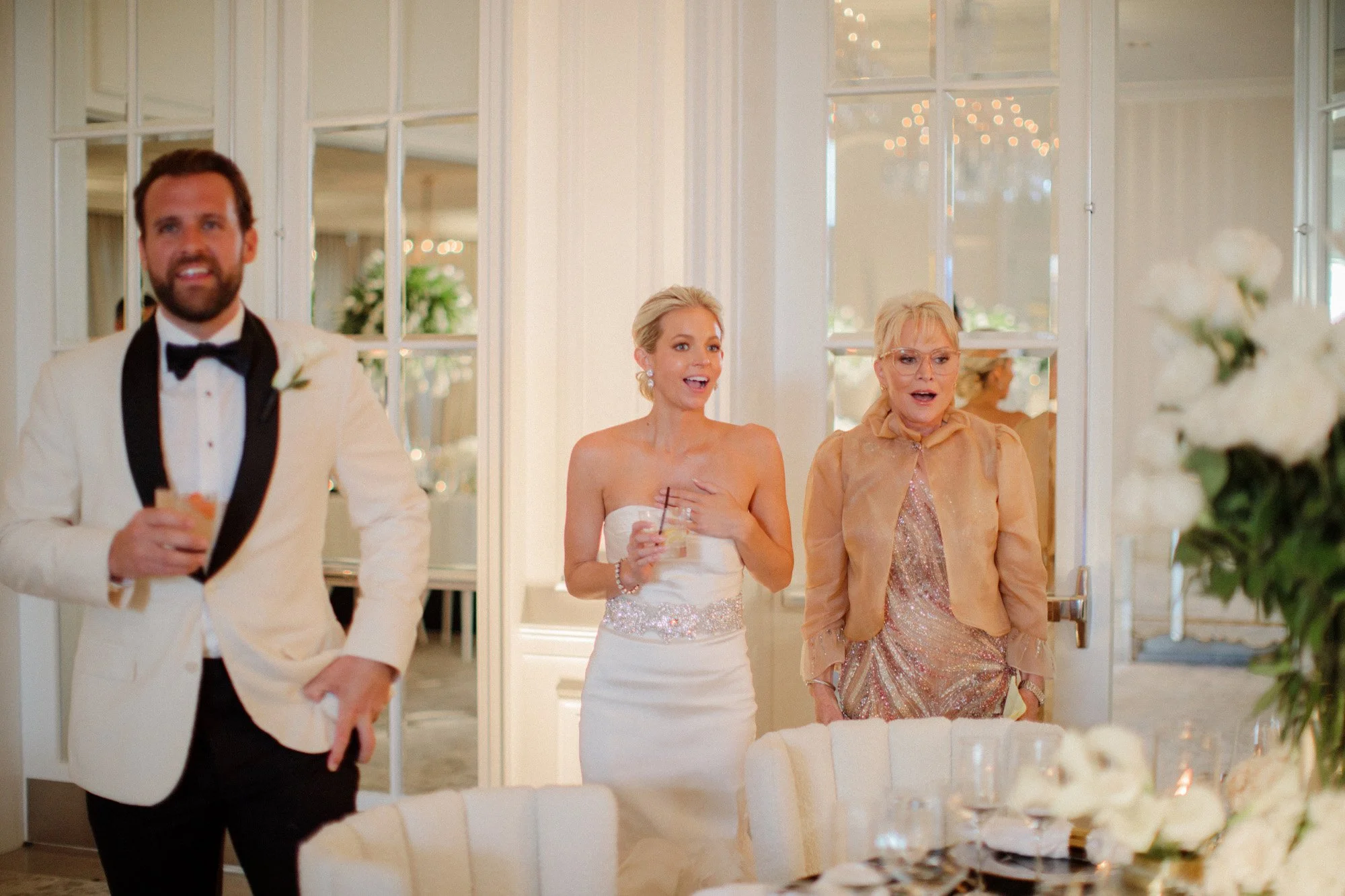 Bride and groom entering wedding reception with bridesmaid at Rosewood Miramar Beach, photographed by Michael & Anna Costa