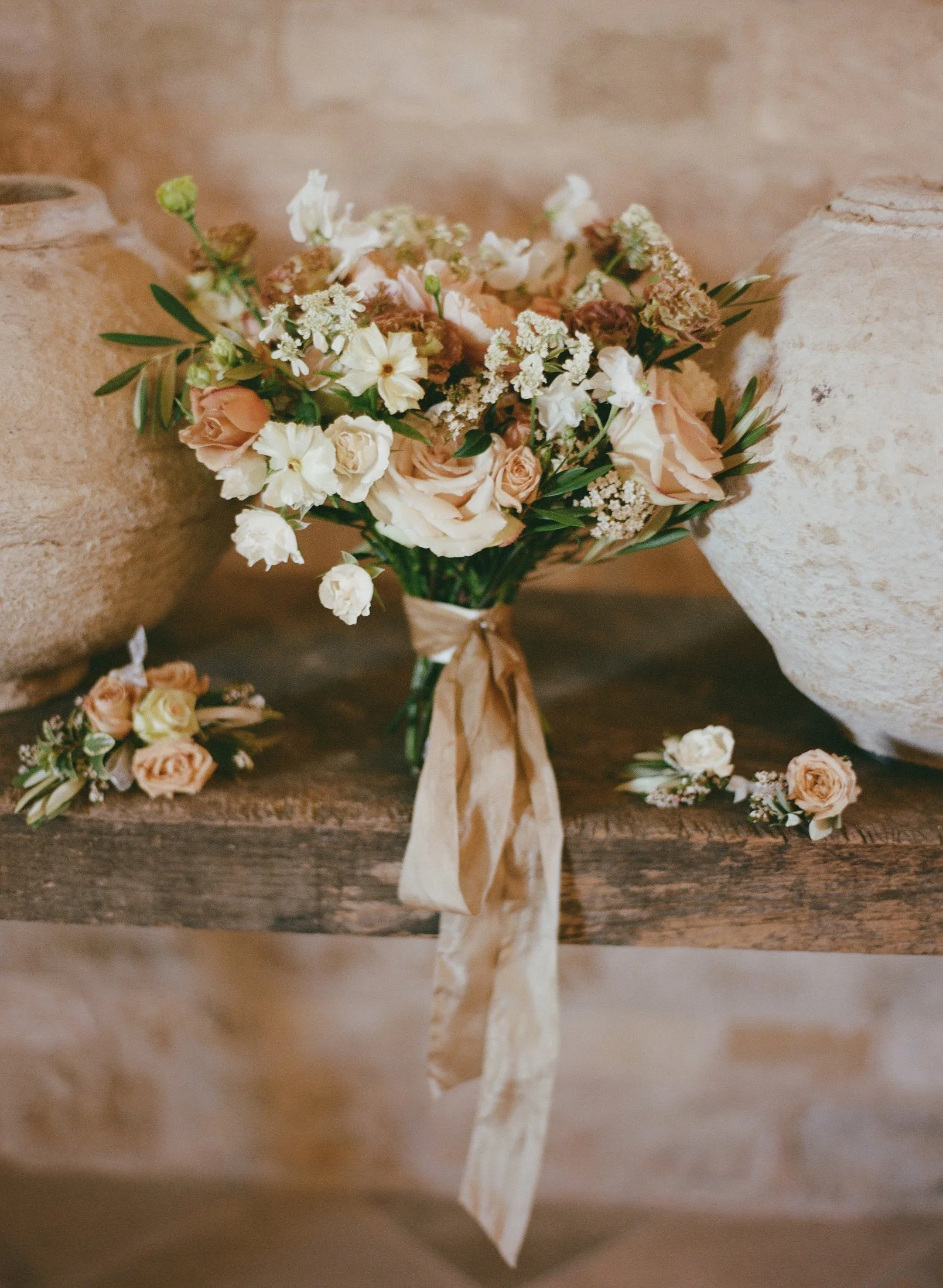 Bridal bouquet with white and peach flowers and ribbon on stone mantel at Sunstone Villa, photographed by Michael & Anna Costa