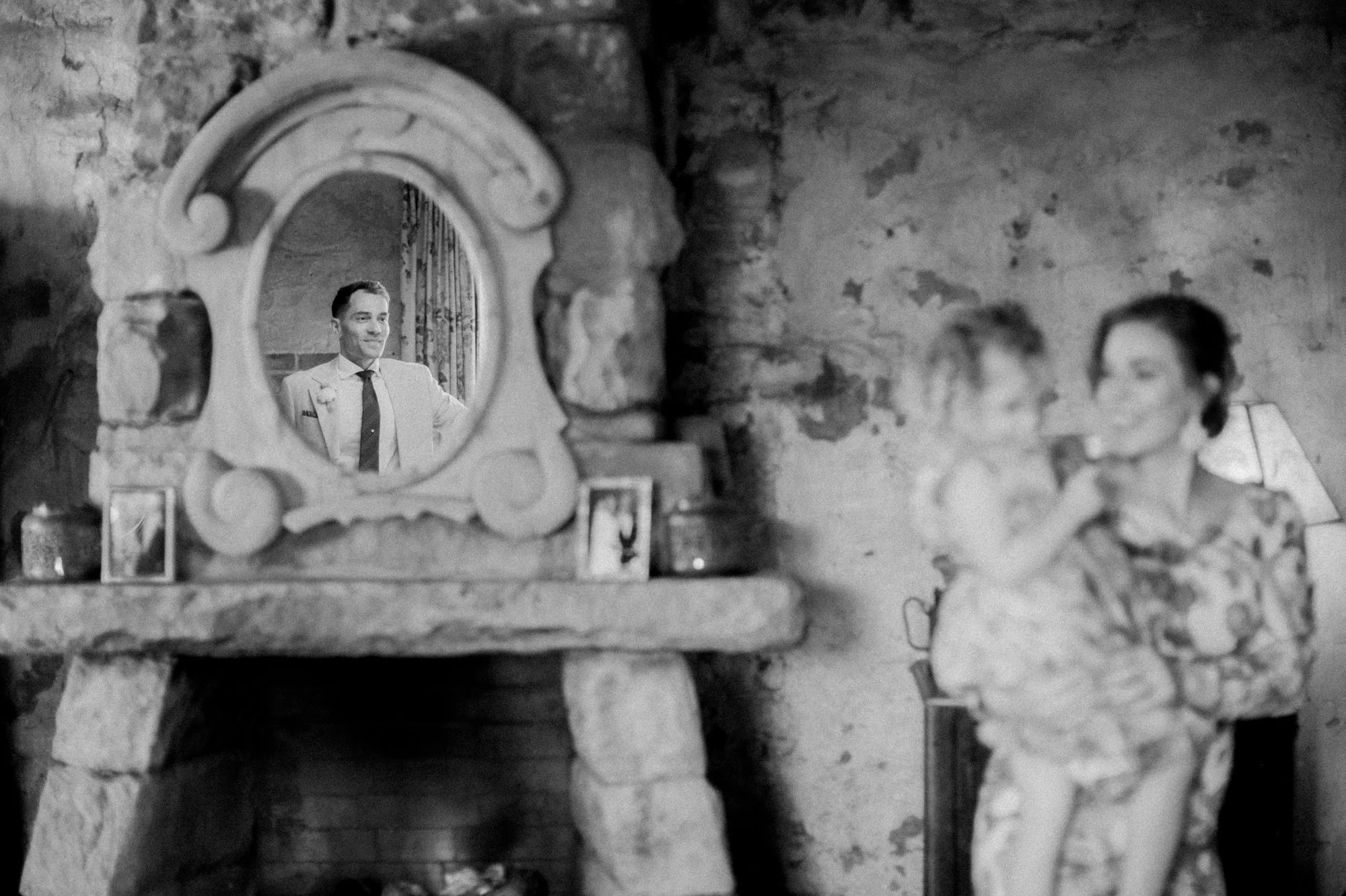Intimate indoor wedding ceremony with bride, groom, and officiant standing by a stone fireplace.