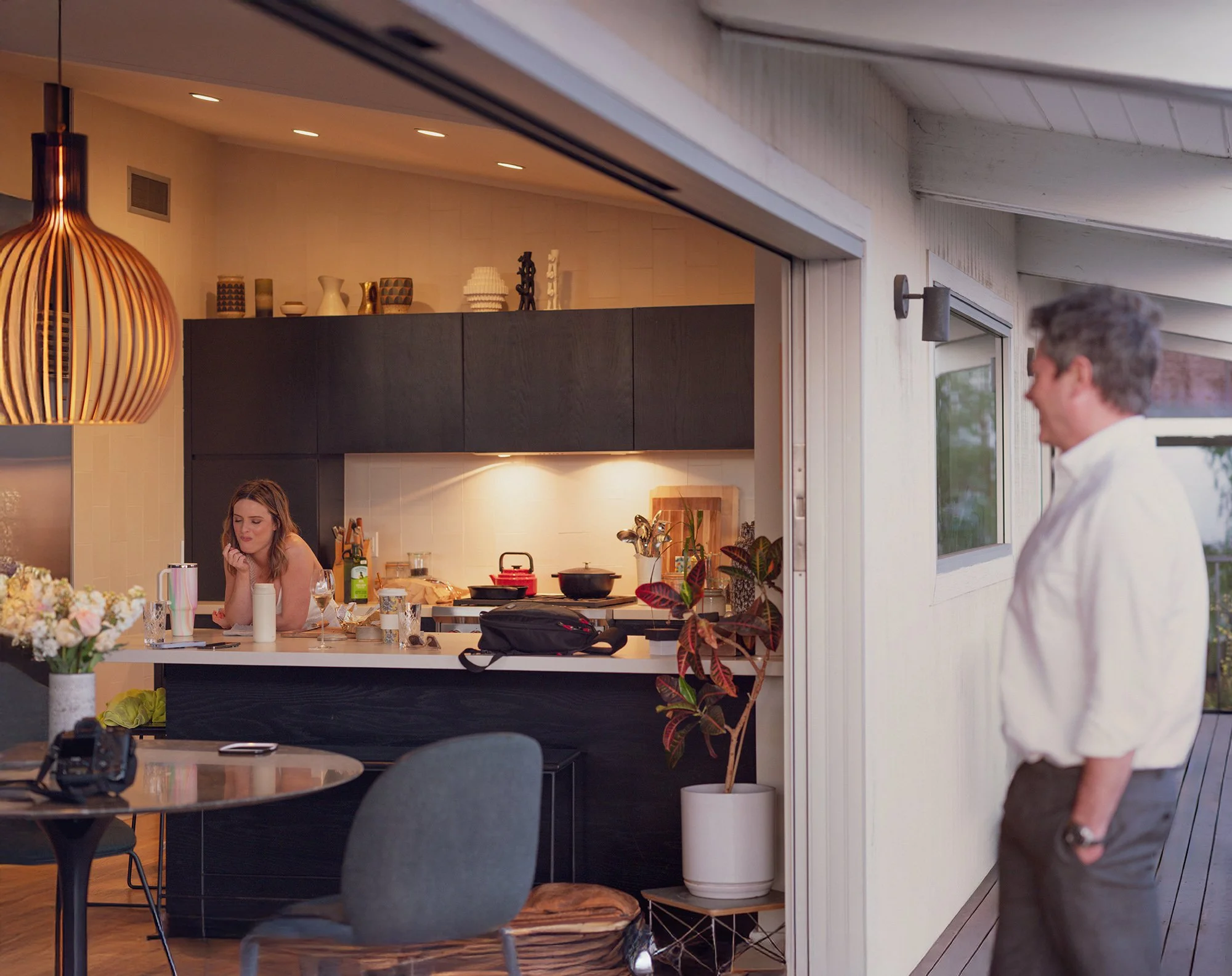 Indoor candid moment of a family gathering in a warmly lit kitchen and dining area.