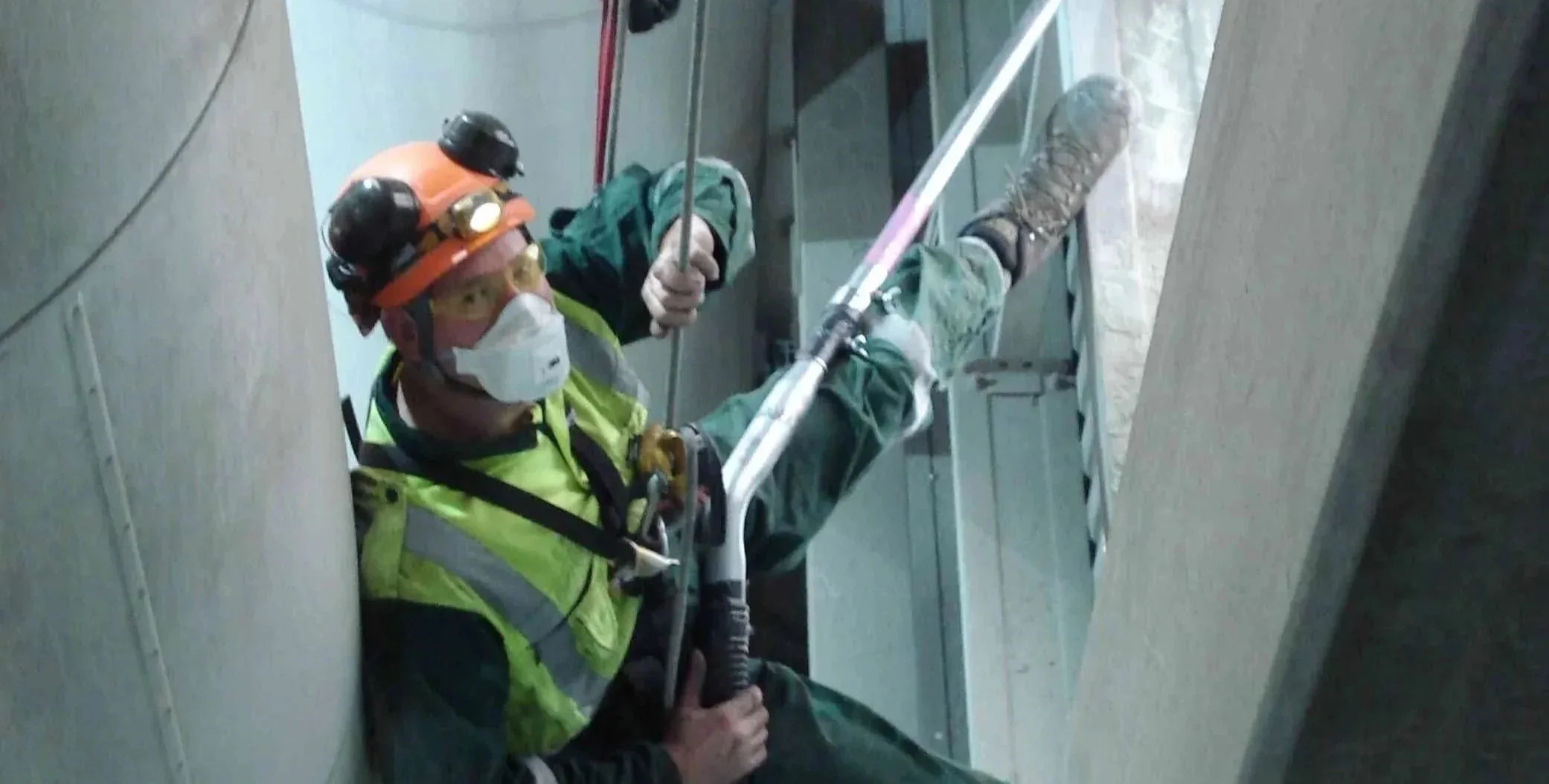 Rope access worker carrying out vacuuming inside a coal-mill building