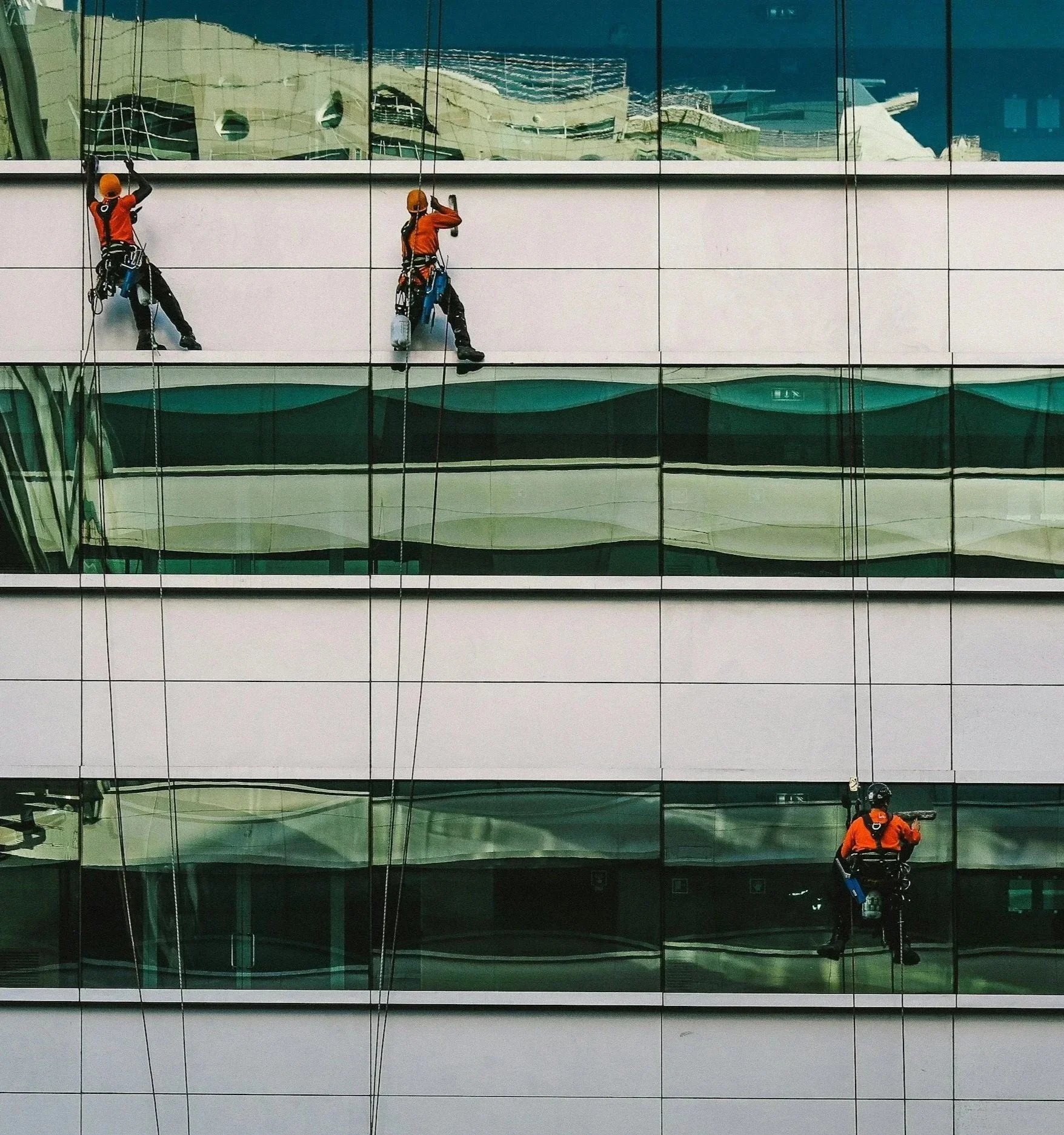 Rope access technicians working on a glass-fronted building