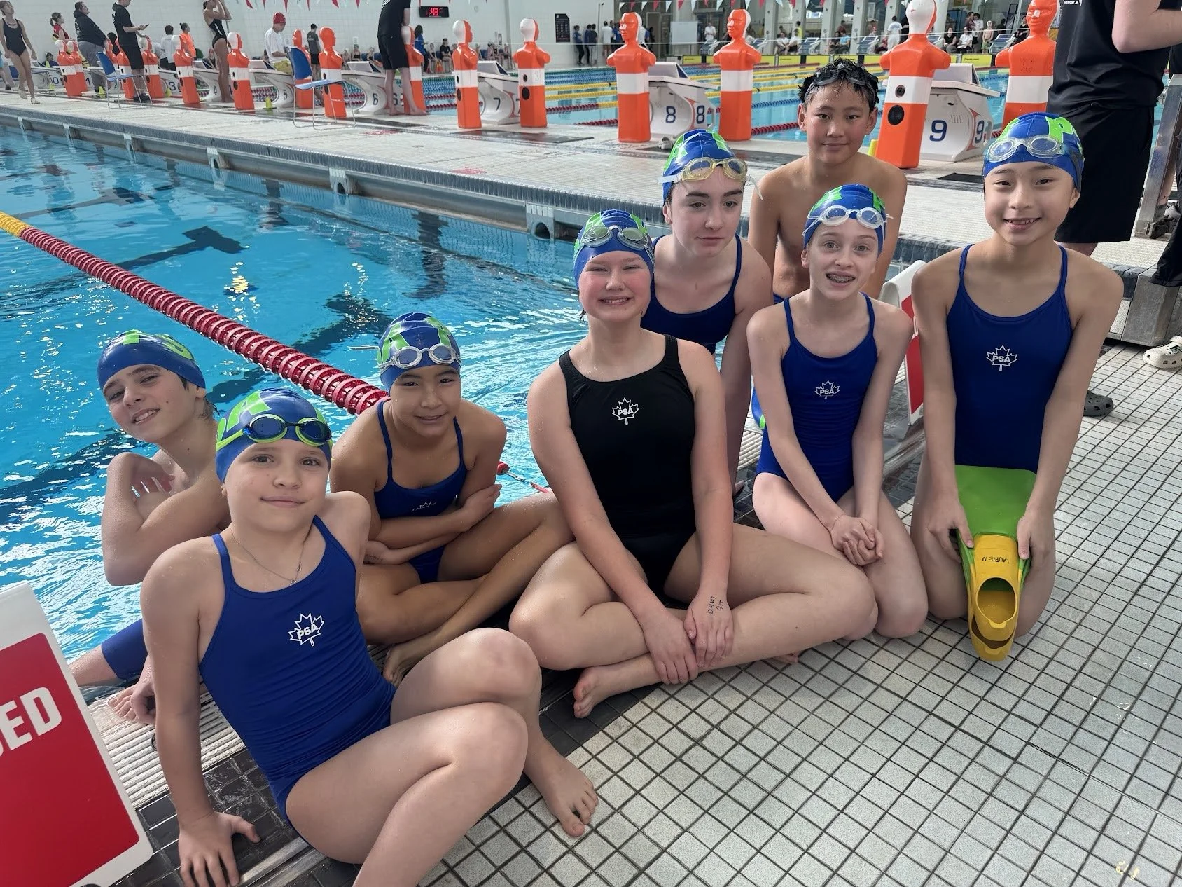 Junior pool lifesaving athletes sitting beside the pool