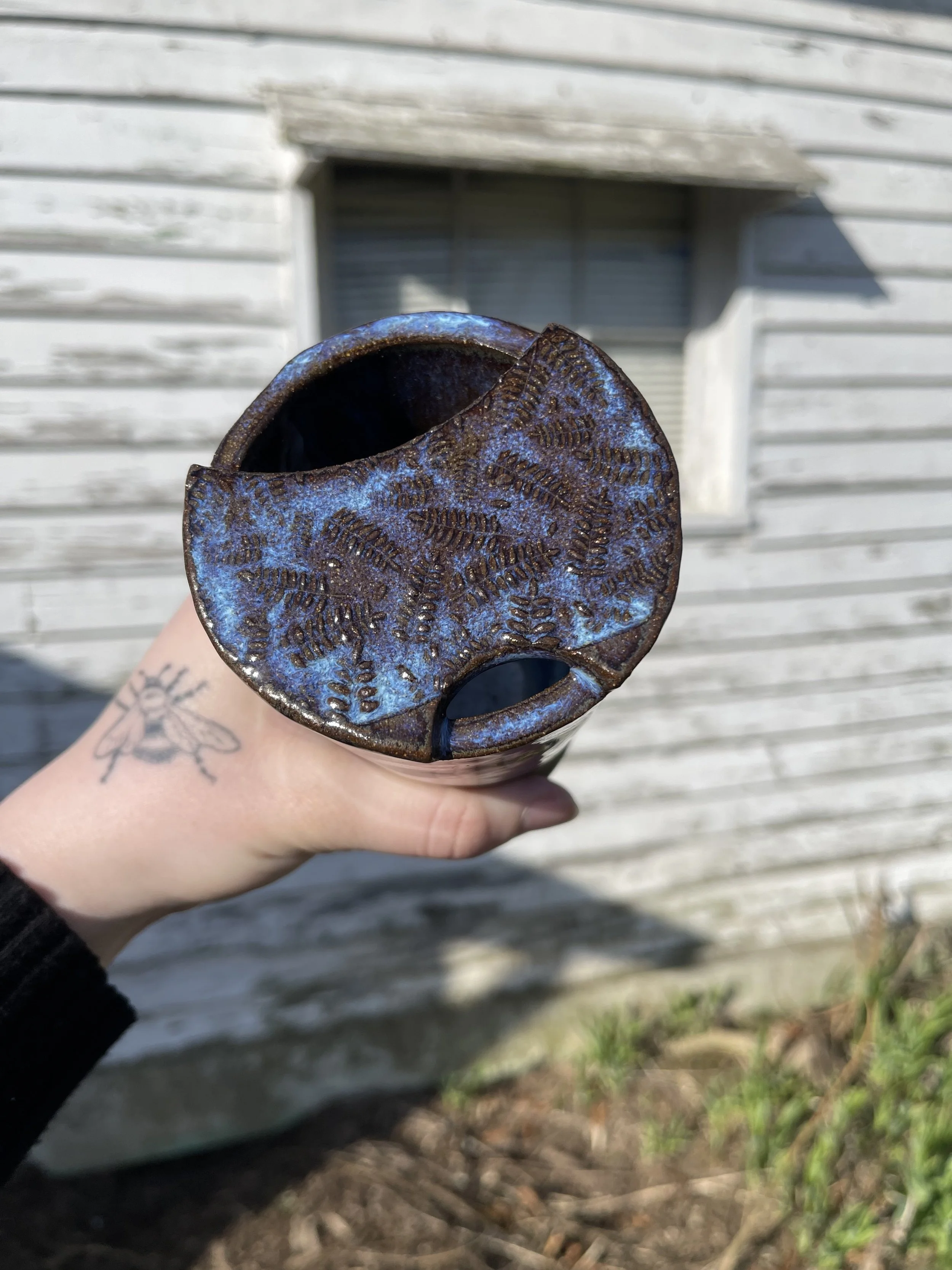 Handmade Ceramic Travel Mug | Dark Glaze Stoneware Tumbler by Stray Cat Studios
Take your brew with a side of mystery. This handbuilt ceramic travel mug features earthy stoneware and a deep, moody glaze—crafted for the curious and caffeinated.