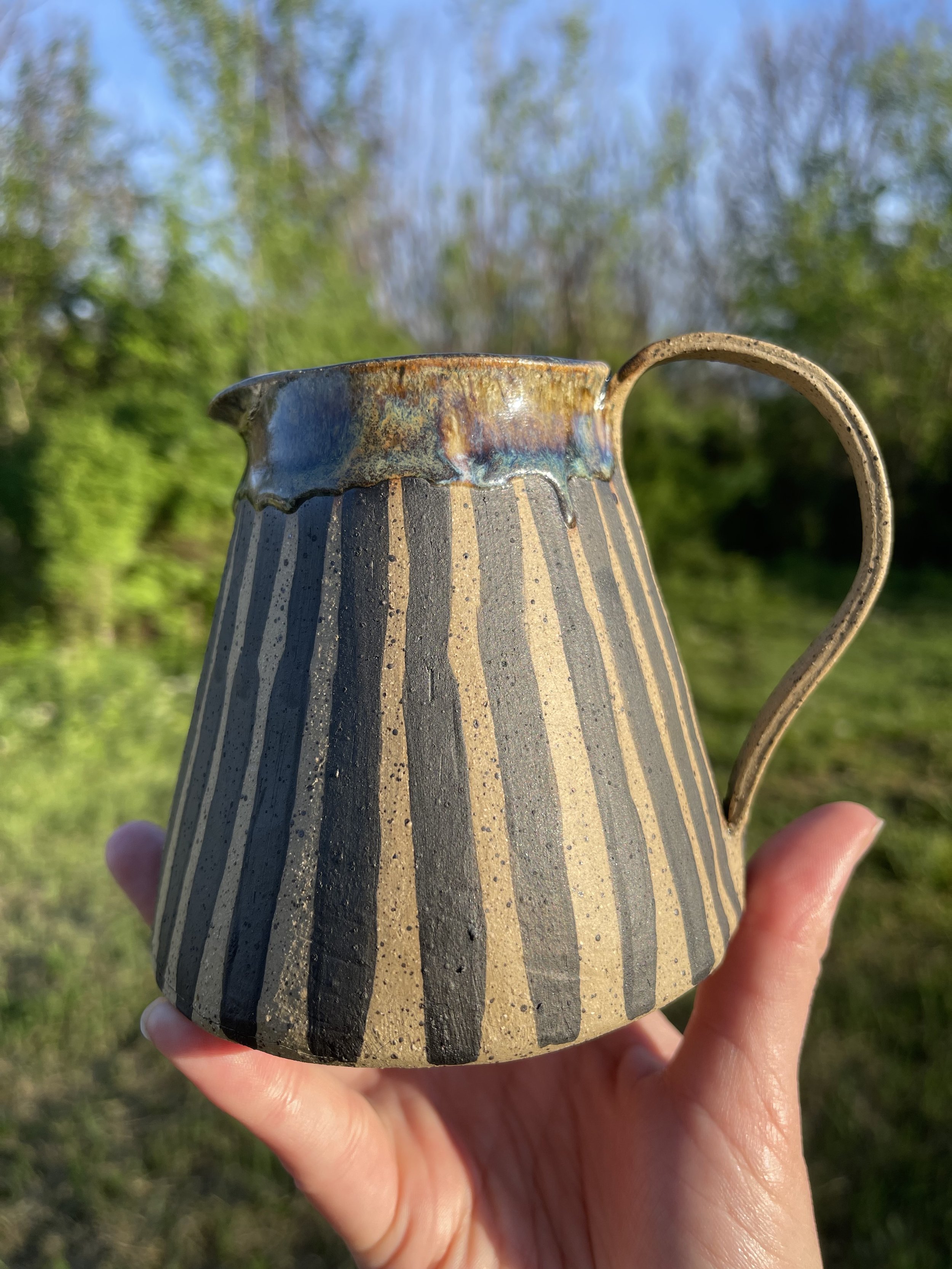 Handcrafted Small Ceramic Pitcher with Bold Stripes and Vibrant Glaze
This one-of-a-kind handcrafted small pitcher features bold black stripes paired with a beautiful drip glaze in rich, earthy hues. Perfect for serving sauces, creamers, or as a stri