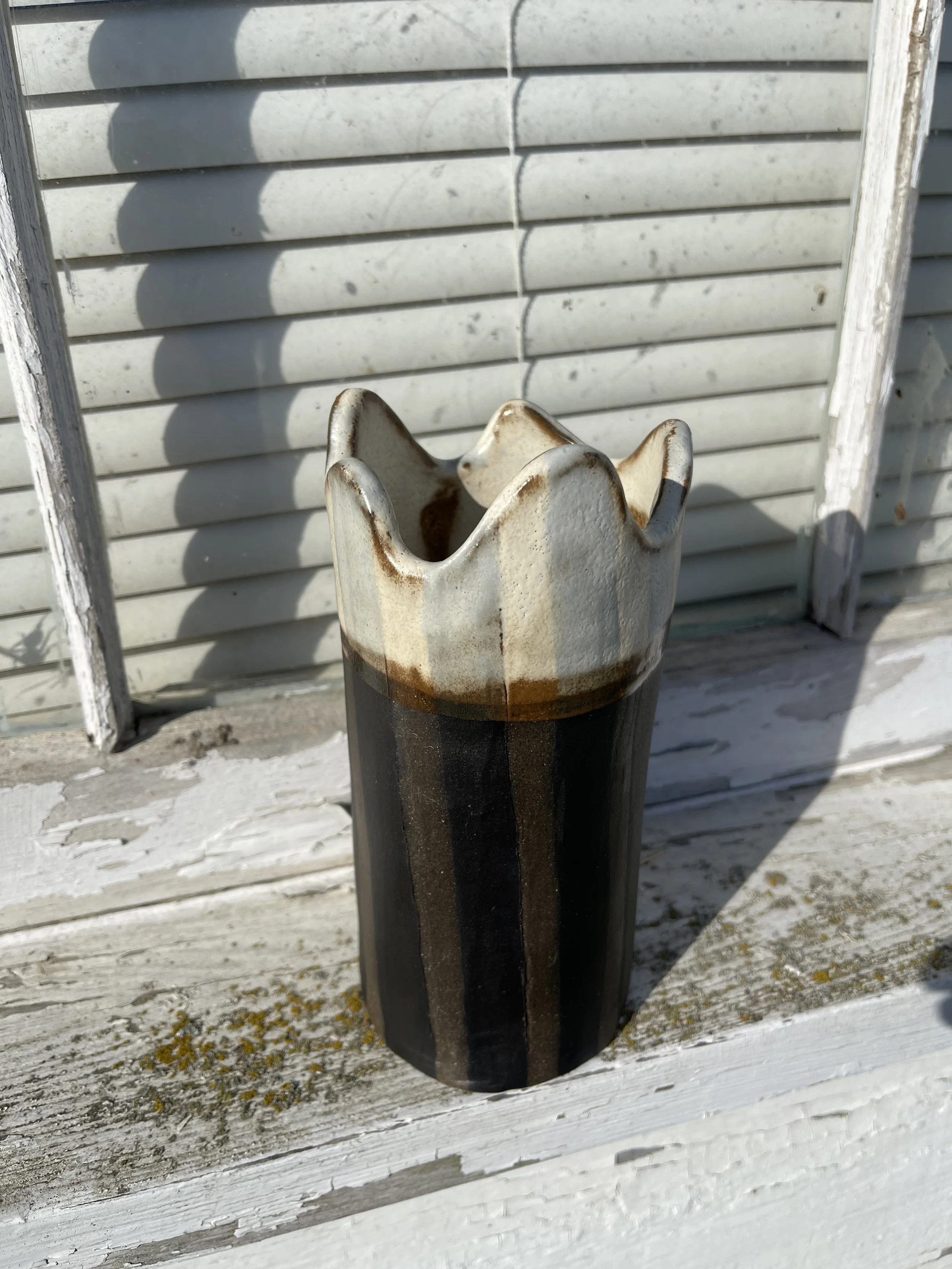 This handmade ceramic vase features bold black-and-white stripes and a sculptural, crown-like rim. Its gothic, whimsical aesthetic makes it perfect for alternative home decor or as a statement piece. Handbuilt and glazed for a one-of-a-kind finish, i