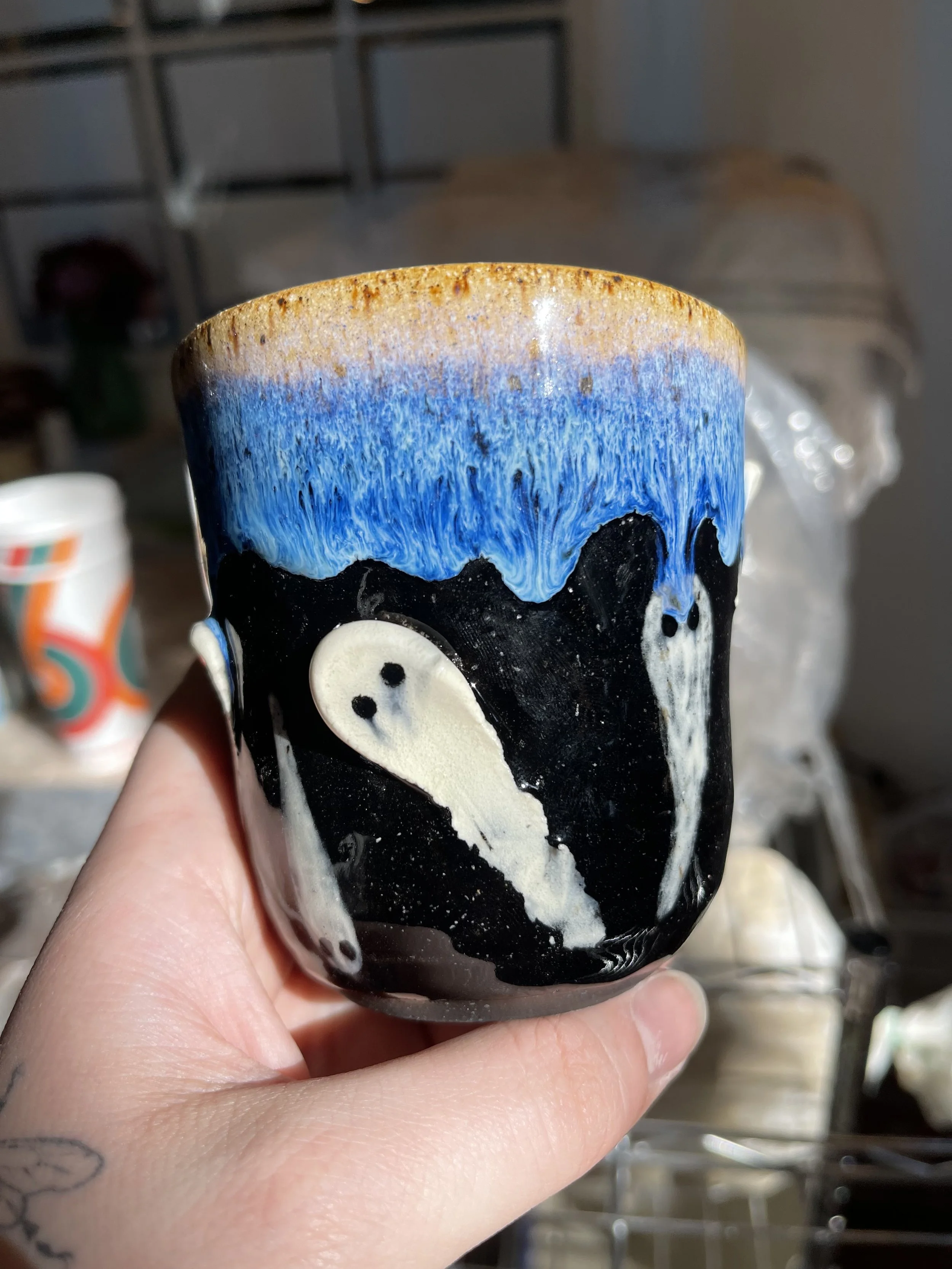 Handmade Ghost Cup | Black & Blue Drip Glaze with Hand-Sculpted Ghosts | Spooky Ceramic Tumbler
This handmade ceramic cup features a high-contrast black base with playful hand-sculpted ghosties peeking through a dreamy blue-and-gold drip glaze. Perfe