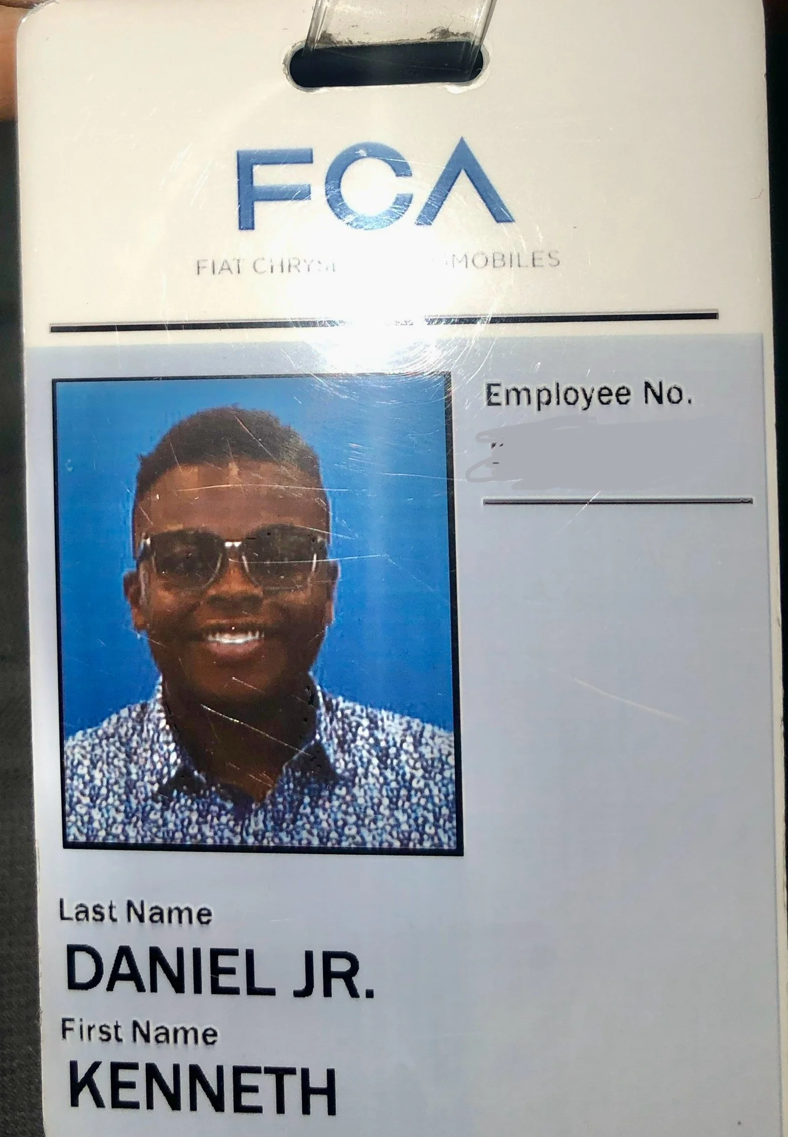 Identification badge for a car dealership, featuring a photo of a smiling man wearing sunglasses and a patterned shirt. The badge includes the logo 'FCA' and the name 'Kenneth Daniel Jr.'