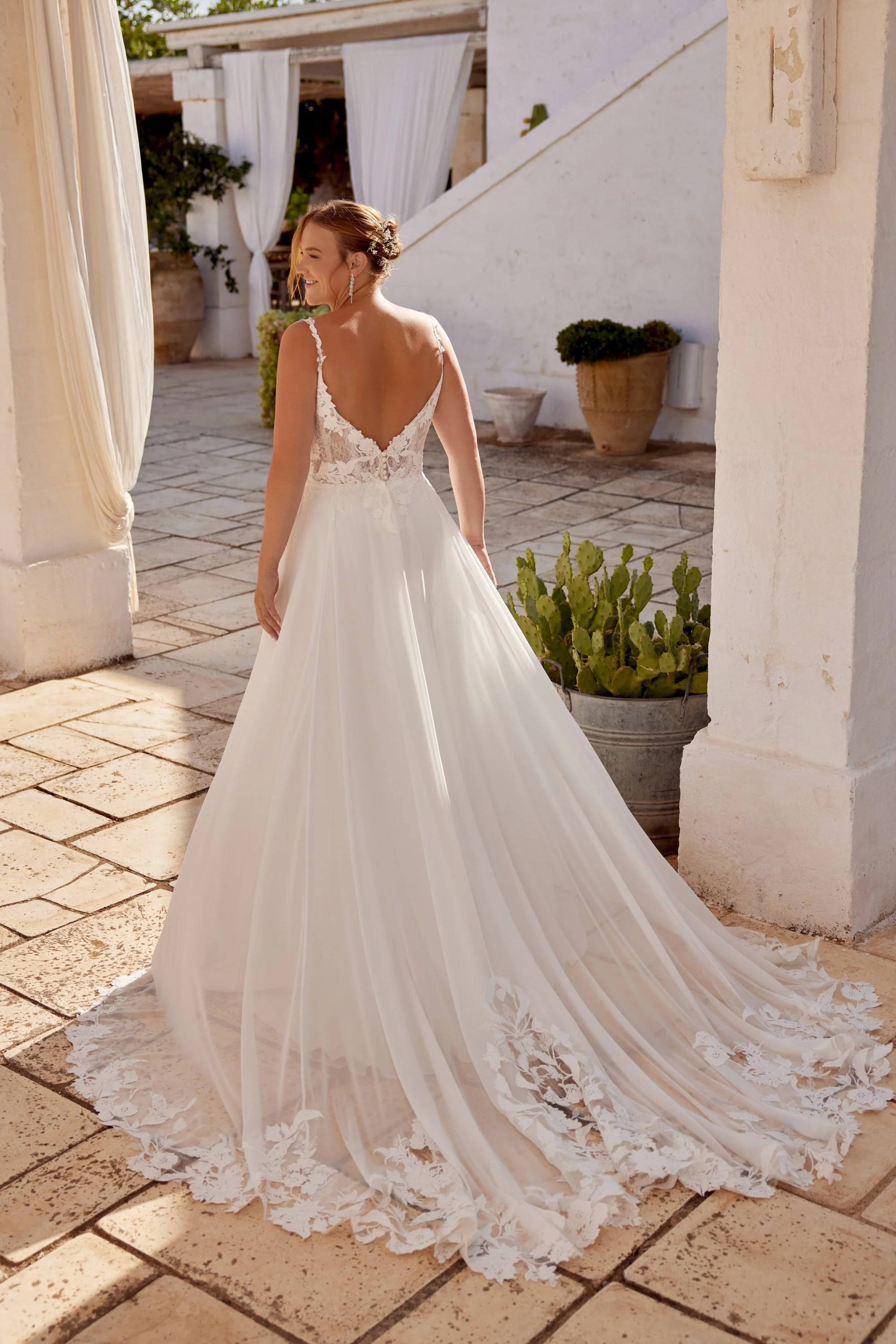 Plus size Lillian West wedding gown with flowing chiffon skirt and floral lace bodice with thin floral straps.