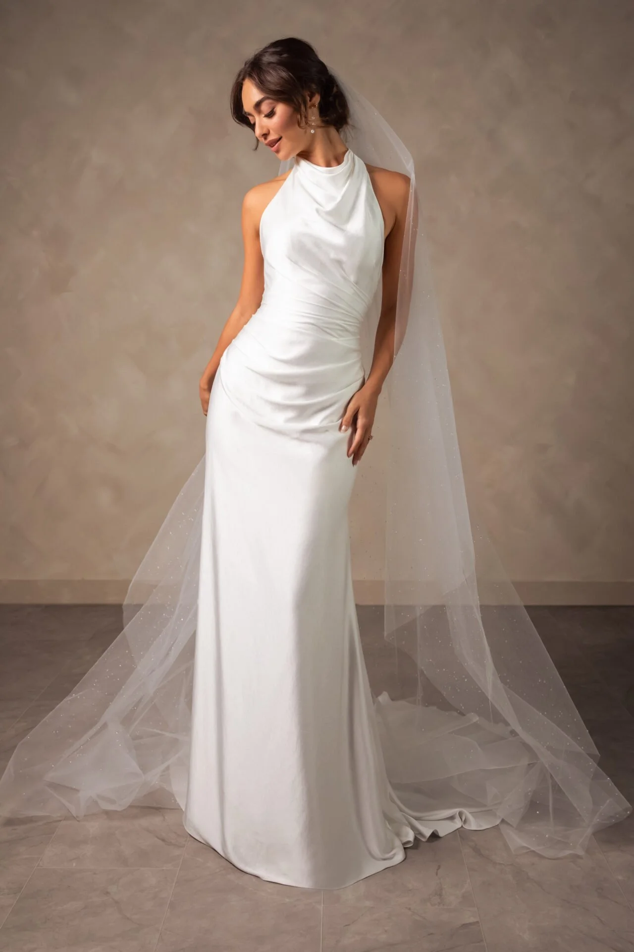 Fitted charmeuse high-neck halter wedding dress by Essense of Australia. Rouged waistline and long cathedral tulle veil.