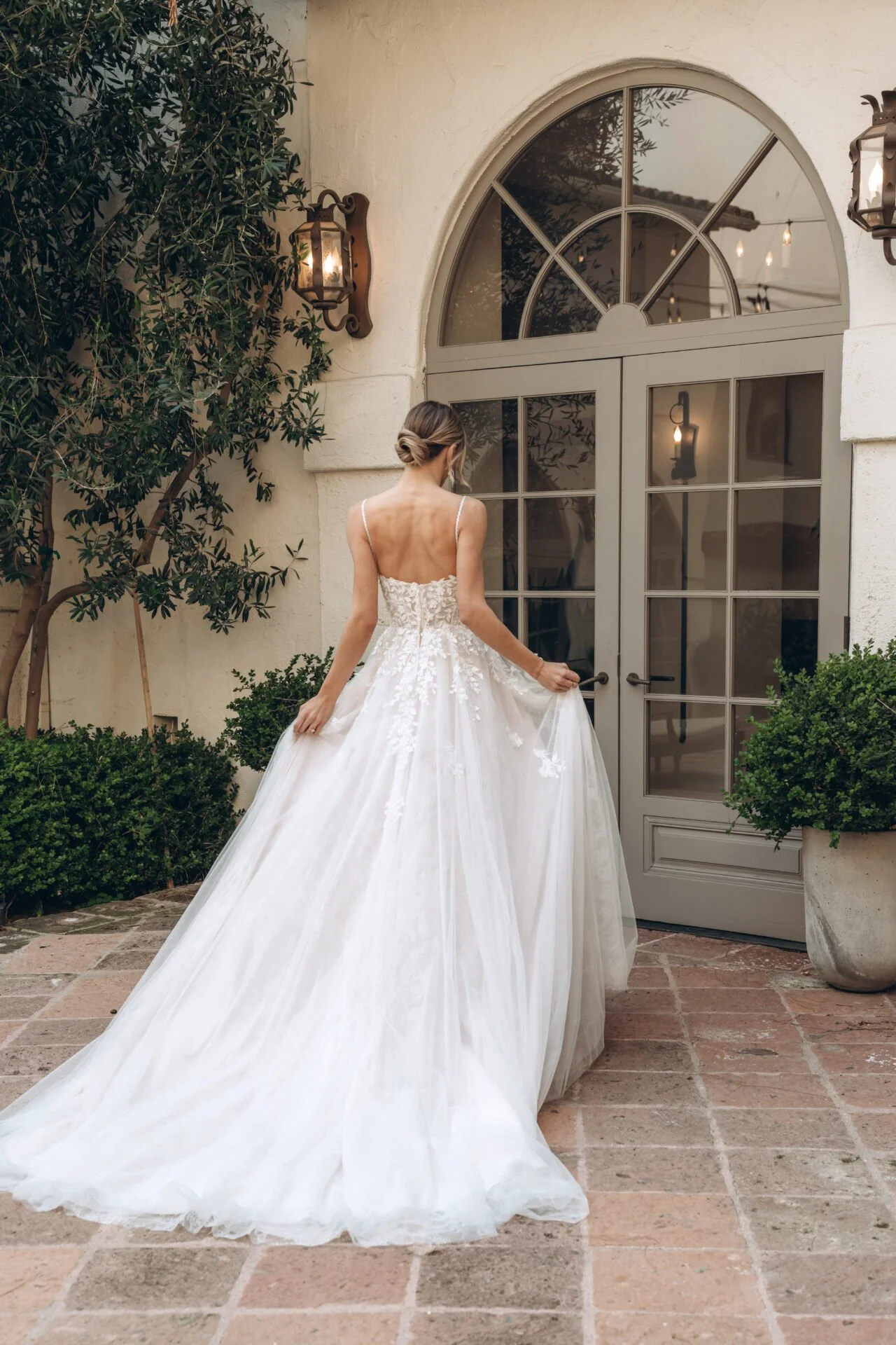 Back of flowing a-line tulle and lace leafy floral Stella York wedding gown with beaded spaghetti straps.
