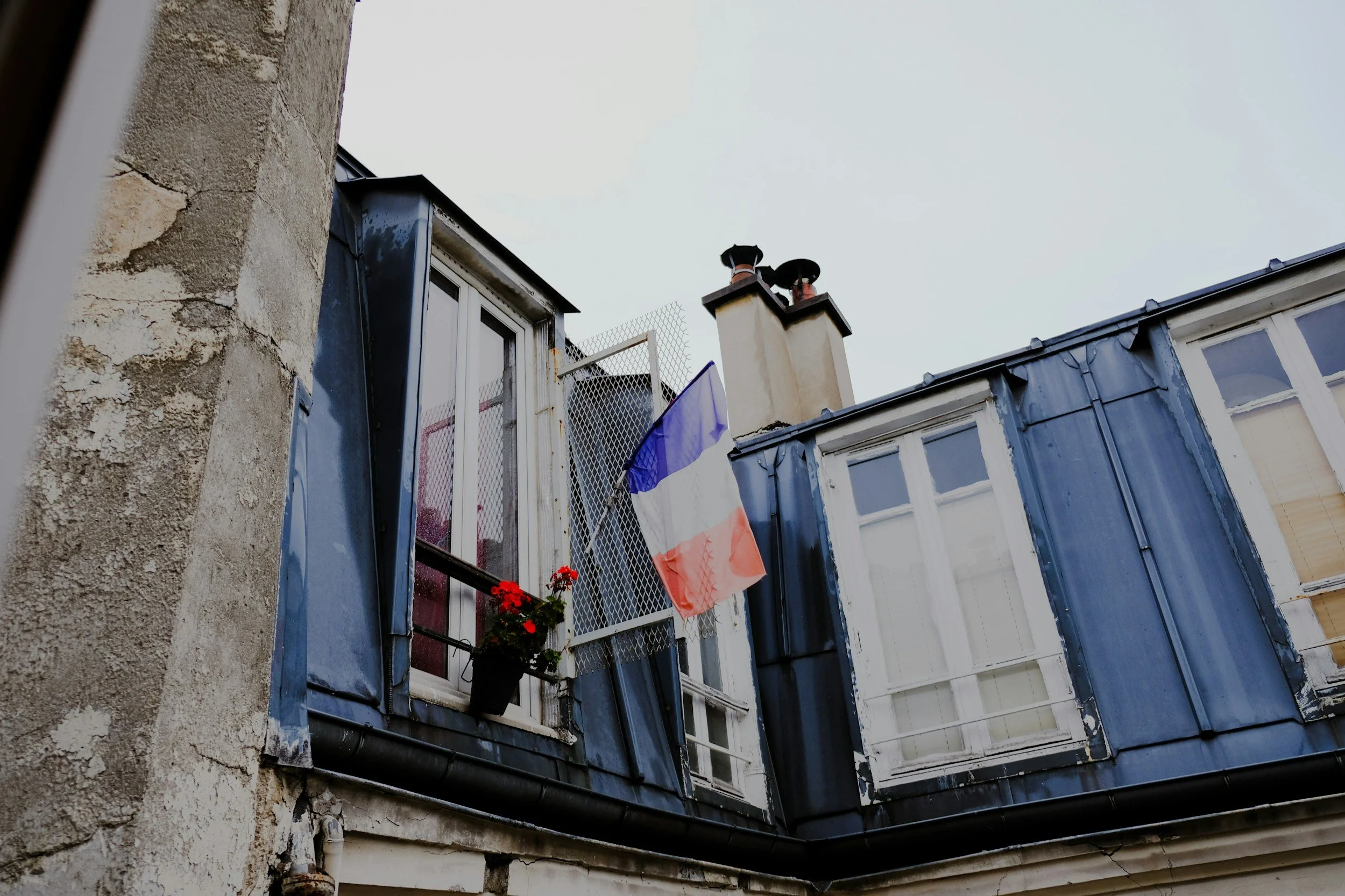 French flag hanging between blue shipping container offices and a weathered building