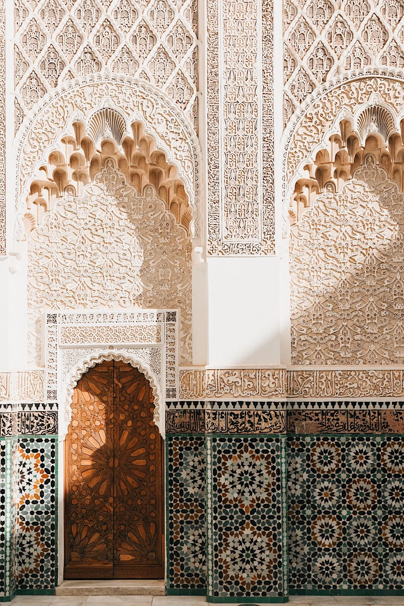 Intricately carved stucco archway and zellige tilework at Ben Youssef Medersa