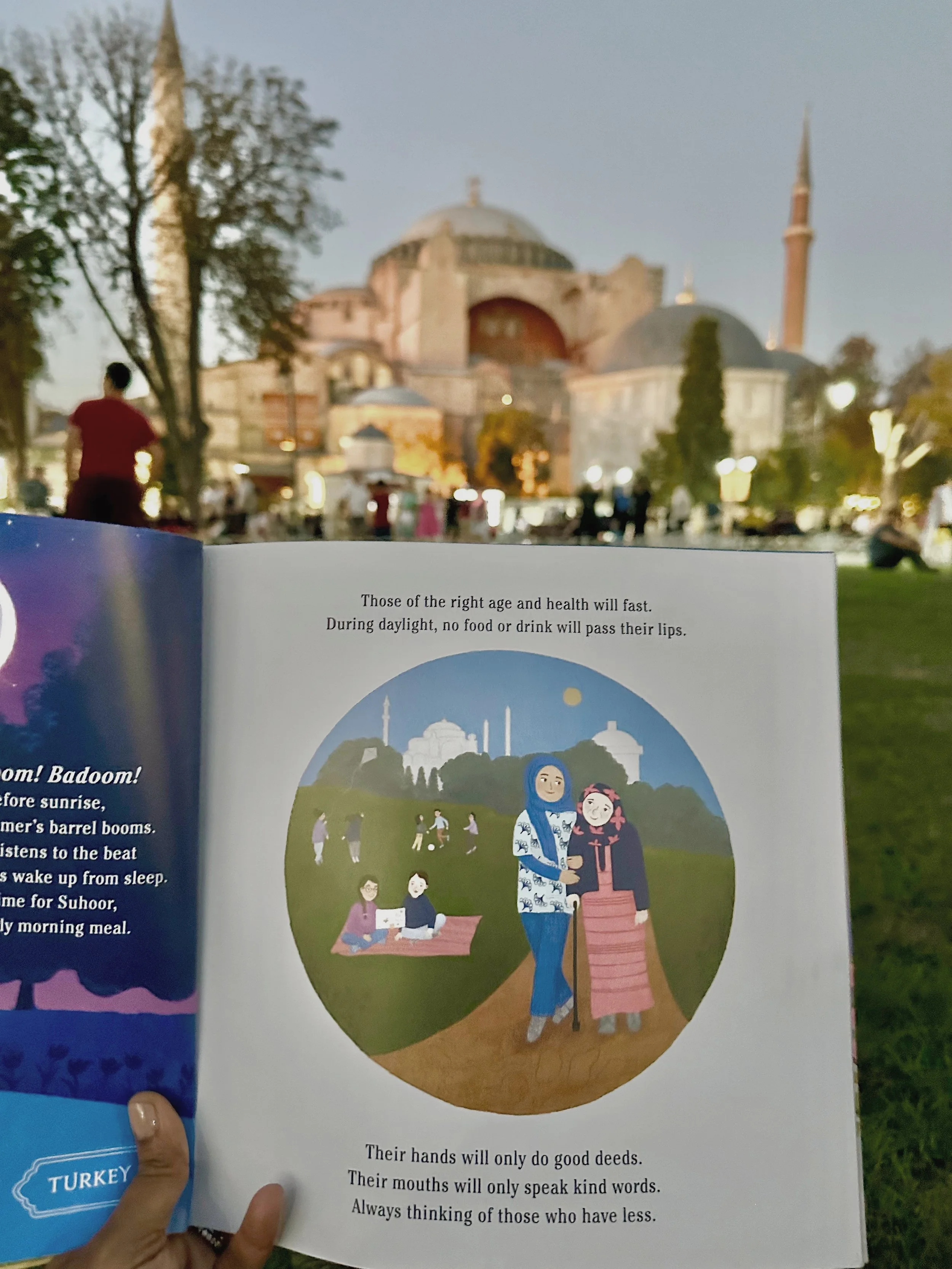 An open children’s book held outdoors with the Hagia Sophia visible in the background.