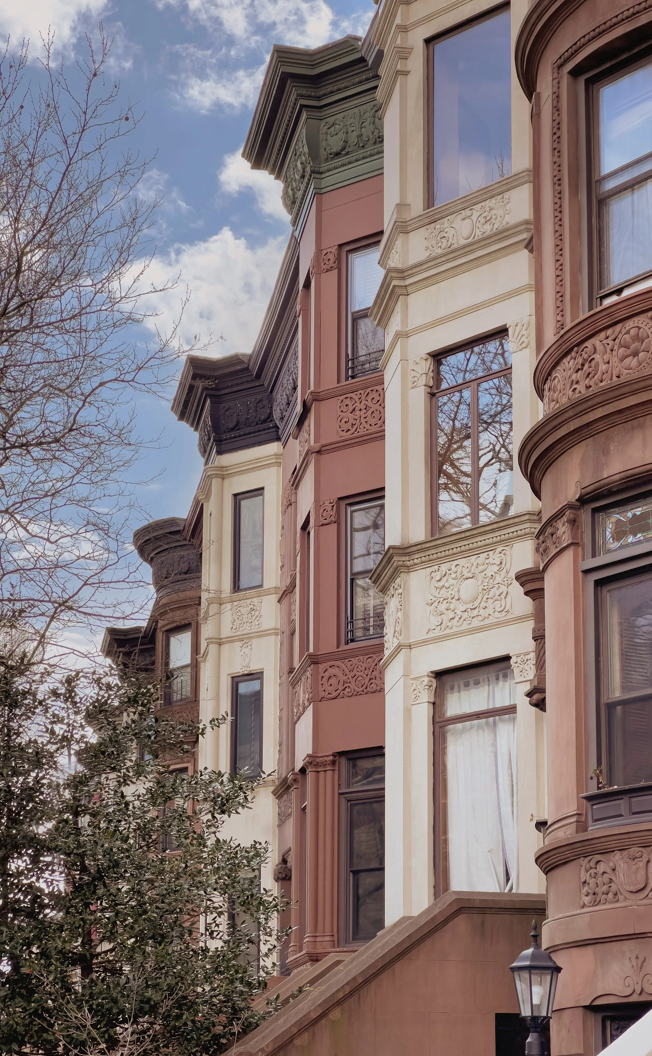 Ornate brownstone rowhouse facades photographed from below against a blue sky, Brooklyn, New York