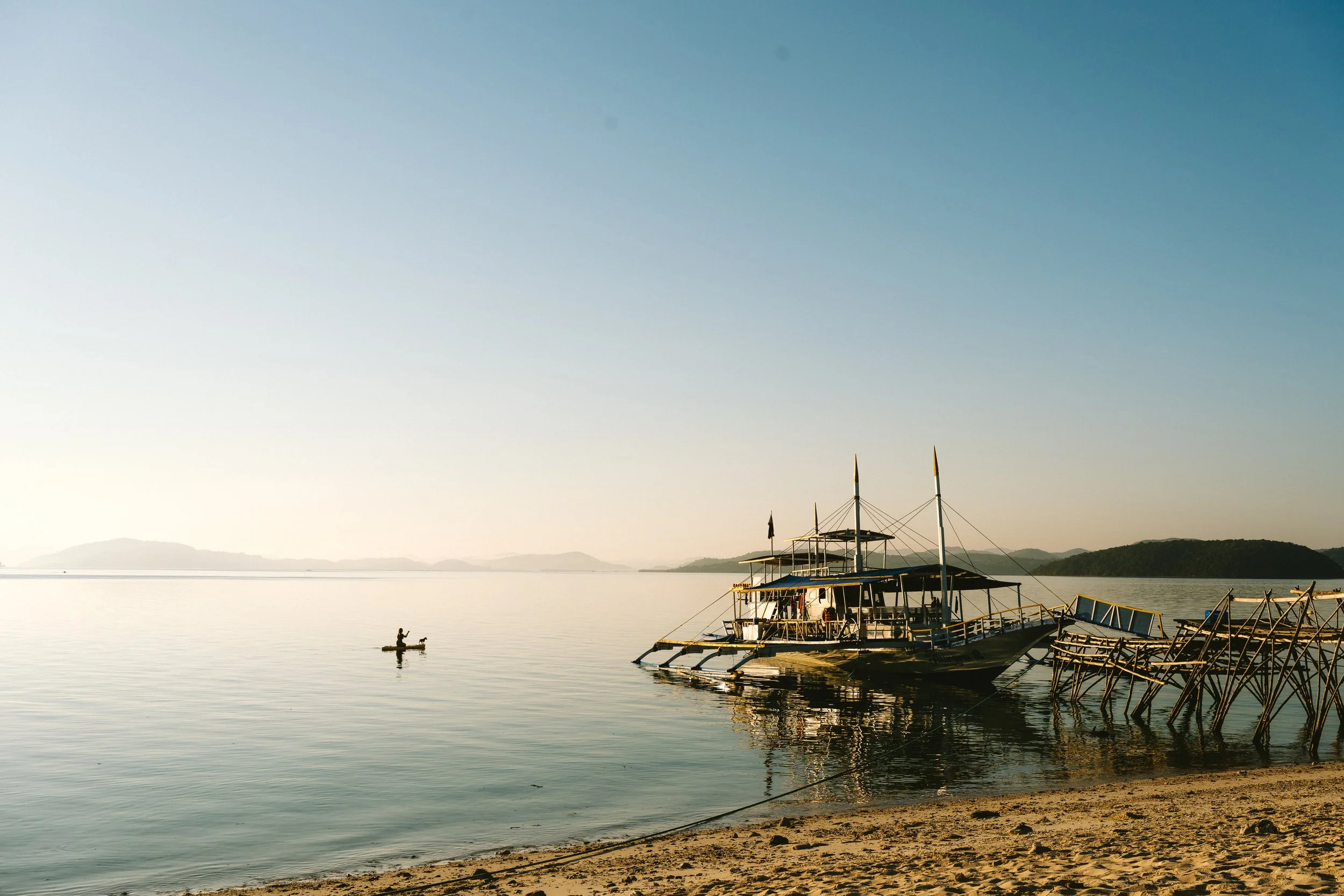 Paddle boarding with dog with Filipino bangka boat at sunrise