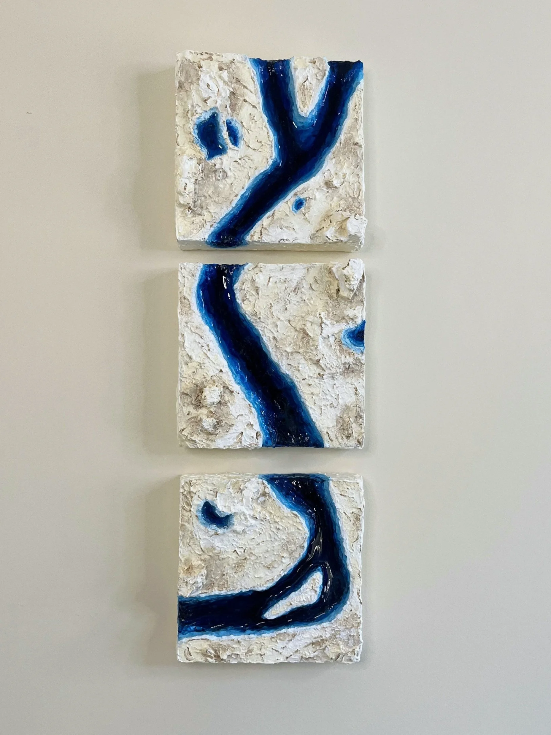 Textured art pieces aligned vertically, each featuring a blue, flowing line on a white and beige background.