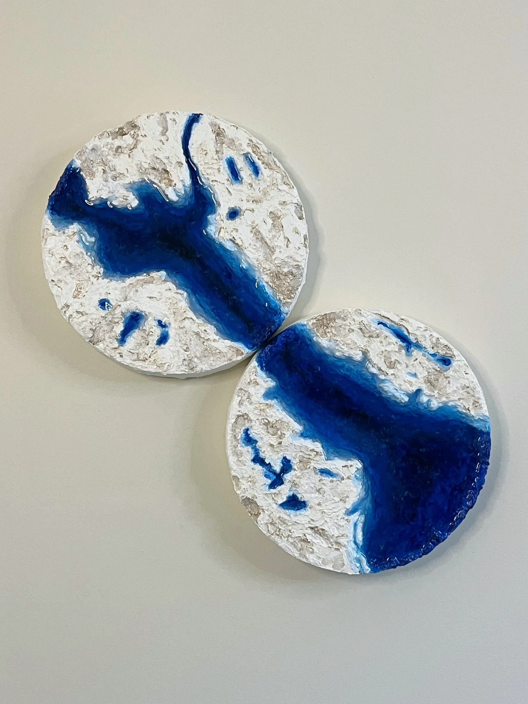 Two circular textured wall art with a white, rocky surface and blue vast river.