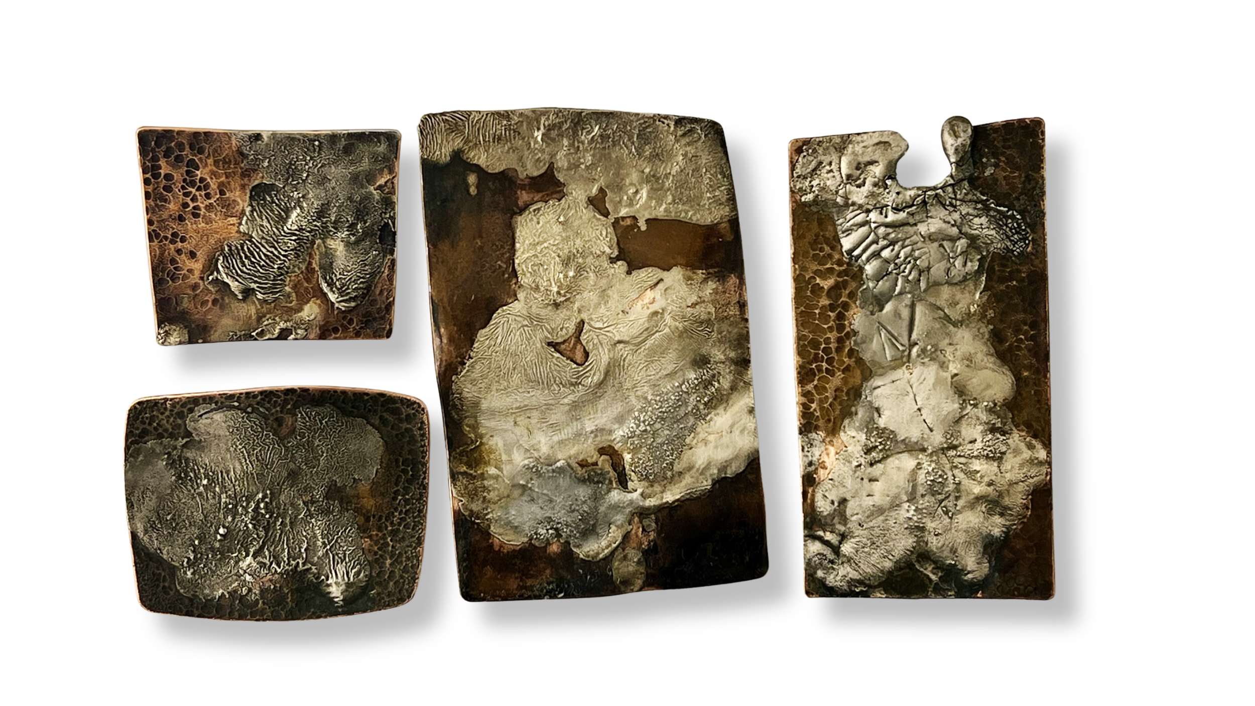 Close-up of five rectangular dual purpose pendant brooches in copper and tin with intricate, organic patterns in earthy tones of brown, beige, and gray.