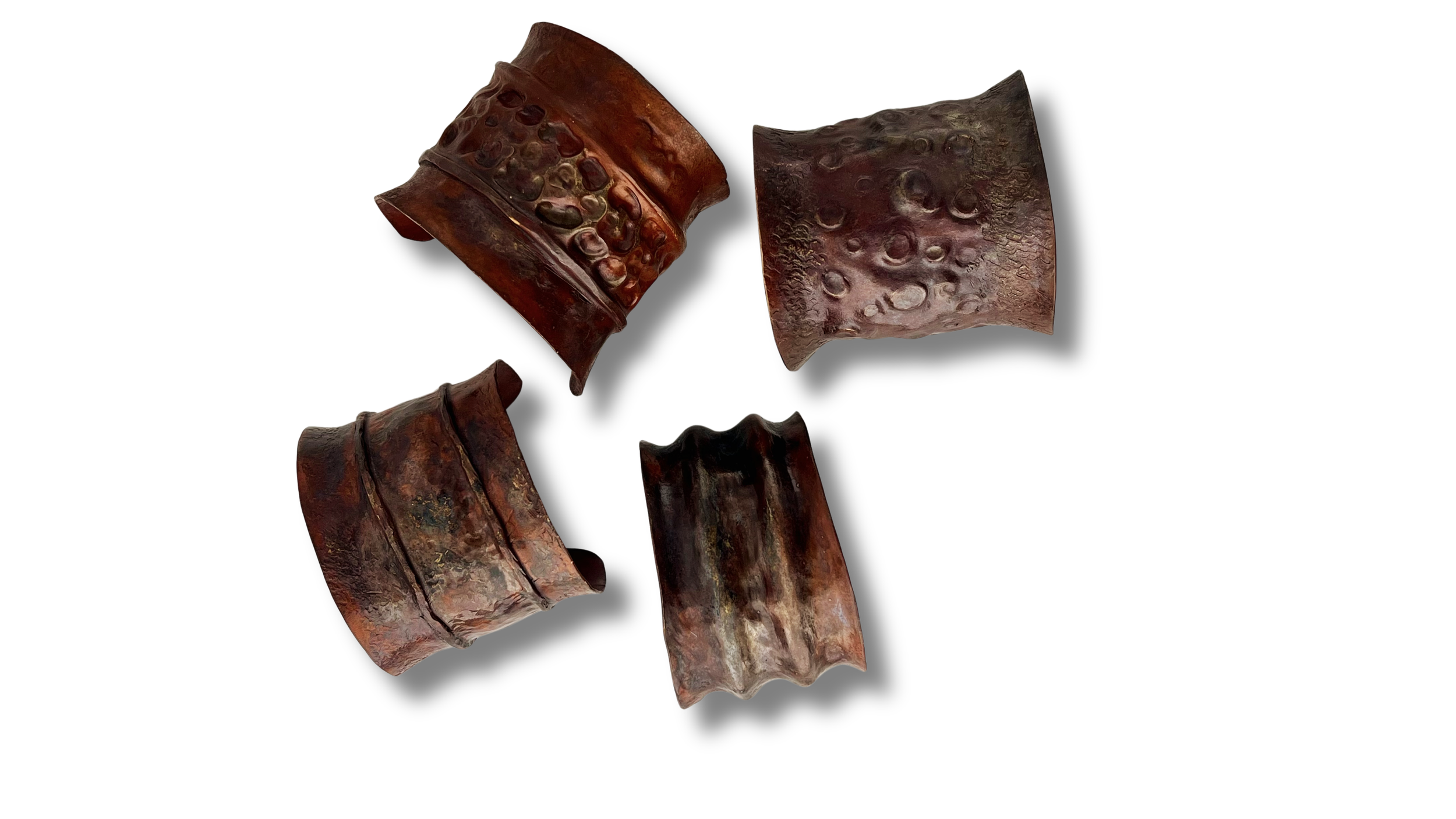 Multiple dark brown, textured, curved metal or ceramic objects with a hammered pattern, isolated on a white background.