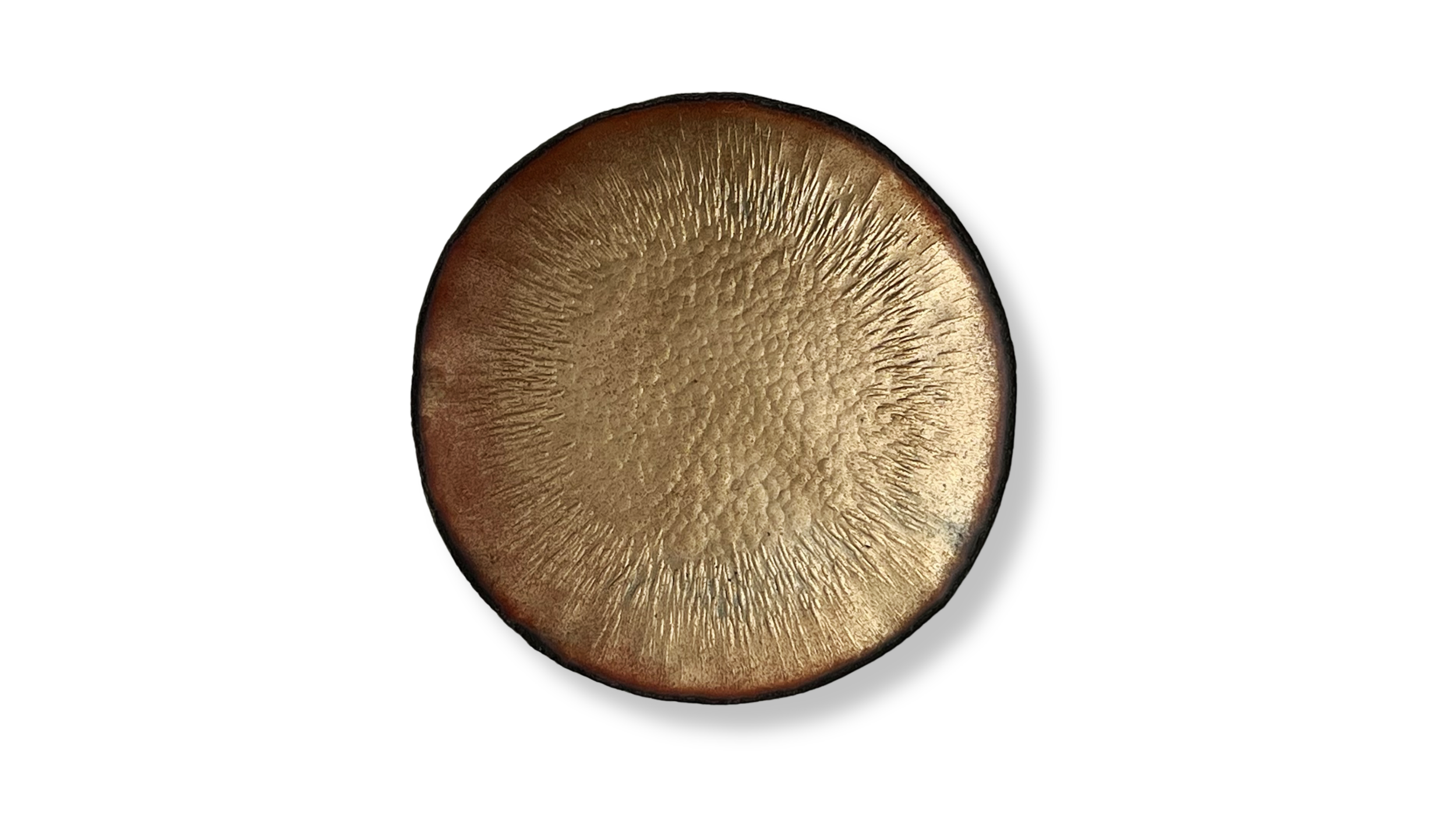 Close-up of a round metallic object with a textured, radial pattern on its golden surface, against a plain white background.