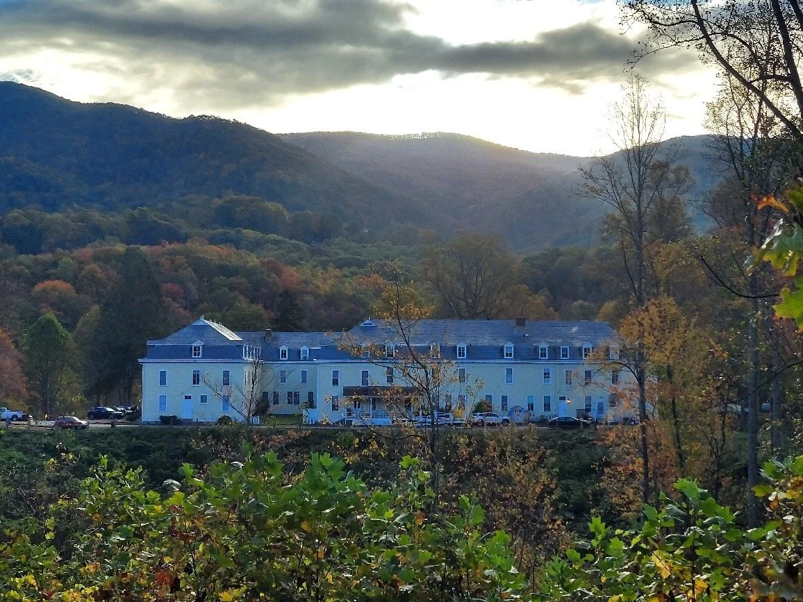 Balsam Mountain Inn surrounded by fall foliage with mountain backdrop