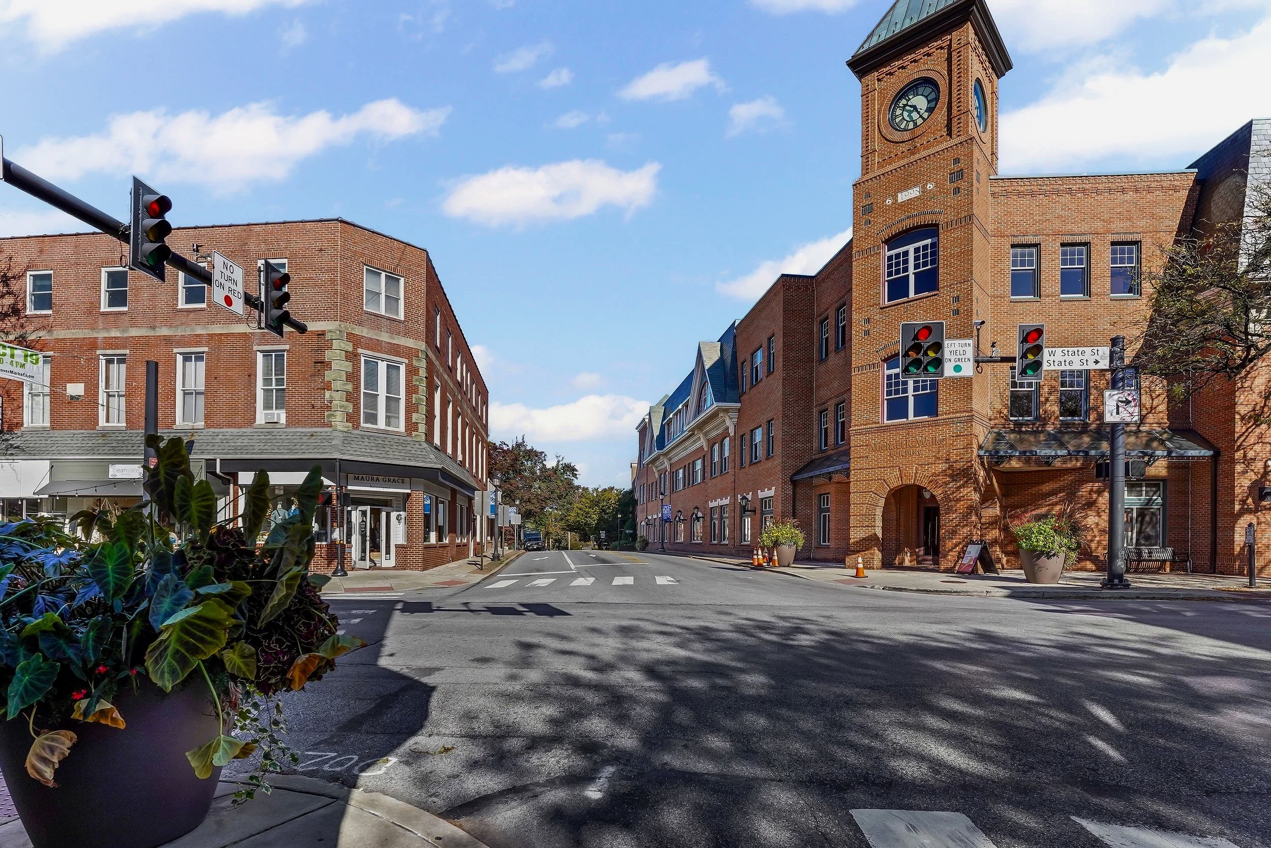 A city street intersection in Chester County with multi-family apartments and retail shops on a sunny day with a few clouds in the sky.