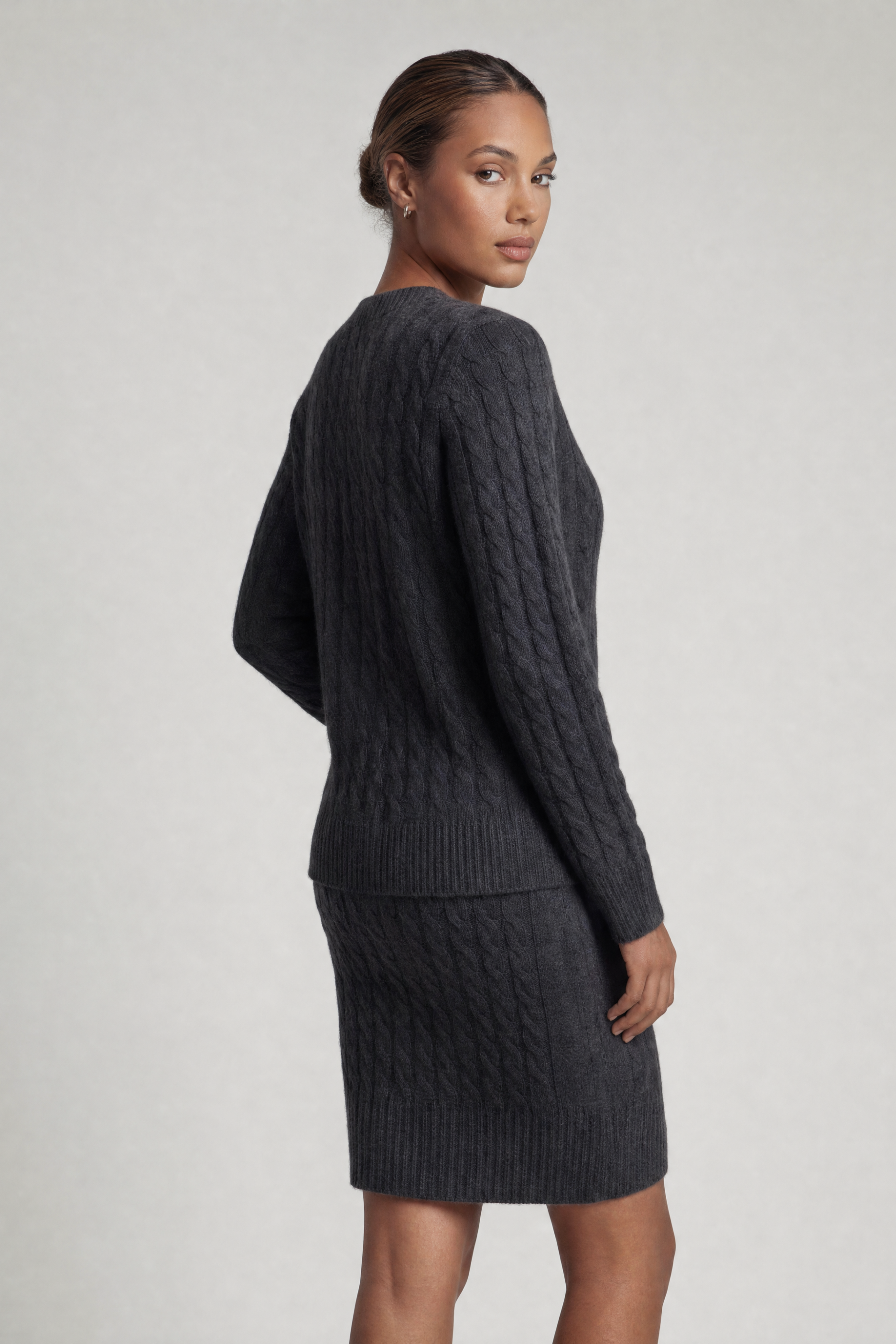 Model wearing cable knit crew neck sweater and matching skirt in Charcoal Gray