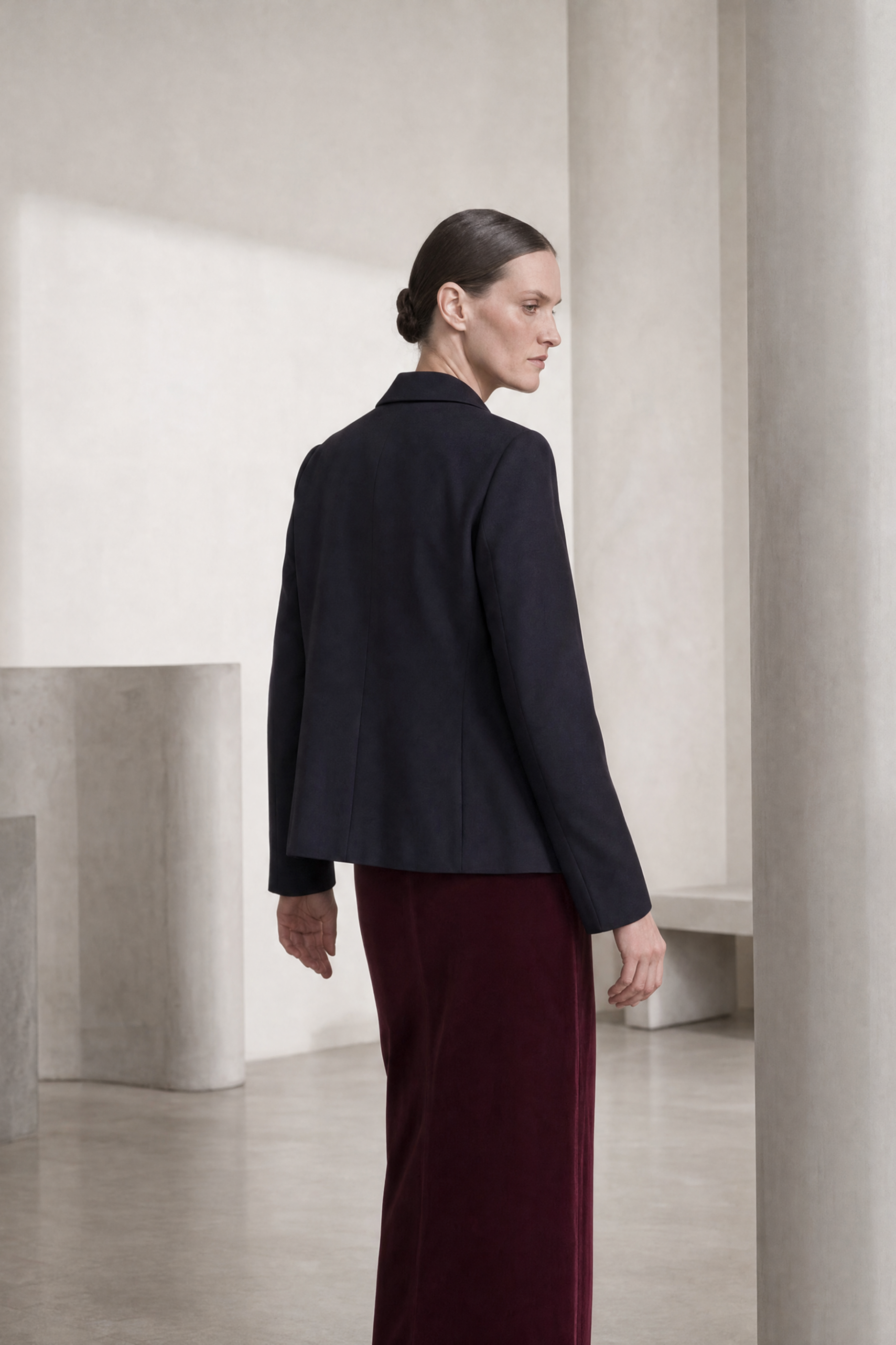 Back of model wearing the black claudia jacket with a cashmere knit and burgundy velvet skirt