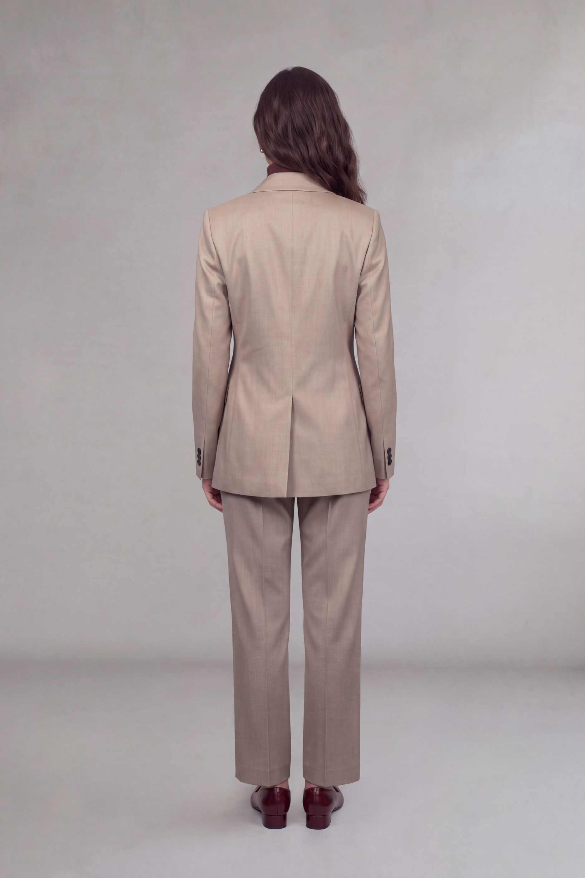 Back of model wearing a tan suit with a center vent