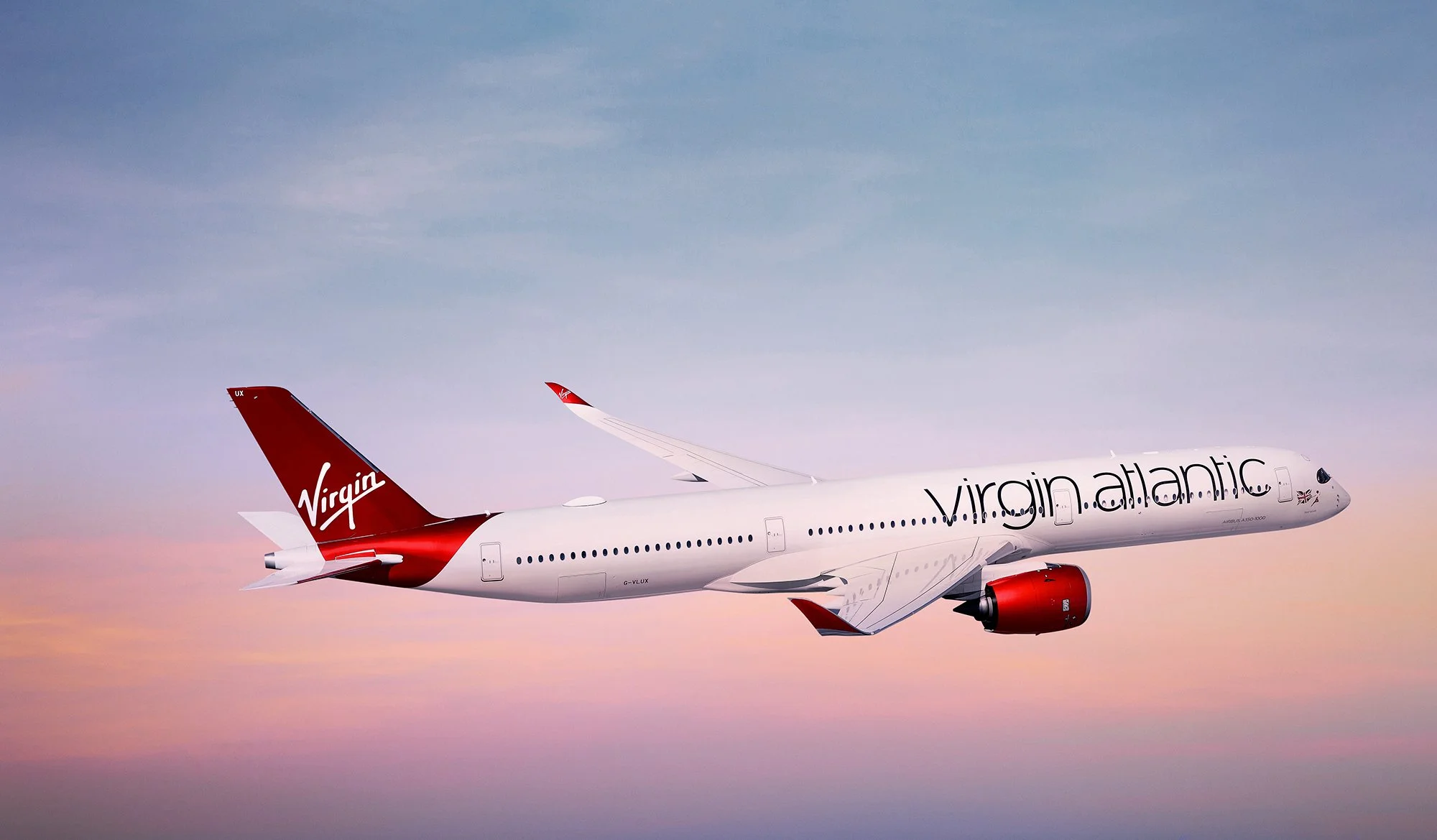 Virgin Atlantic airplane flying in the sky at sunset.