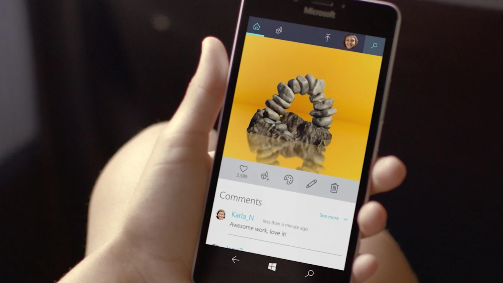A person holding a smartphone displaying an art photo of rocks arranged in an arch with a yellow background.