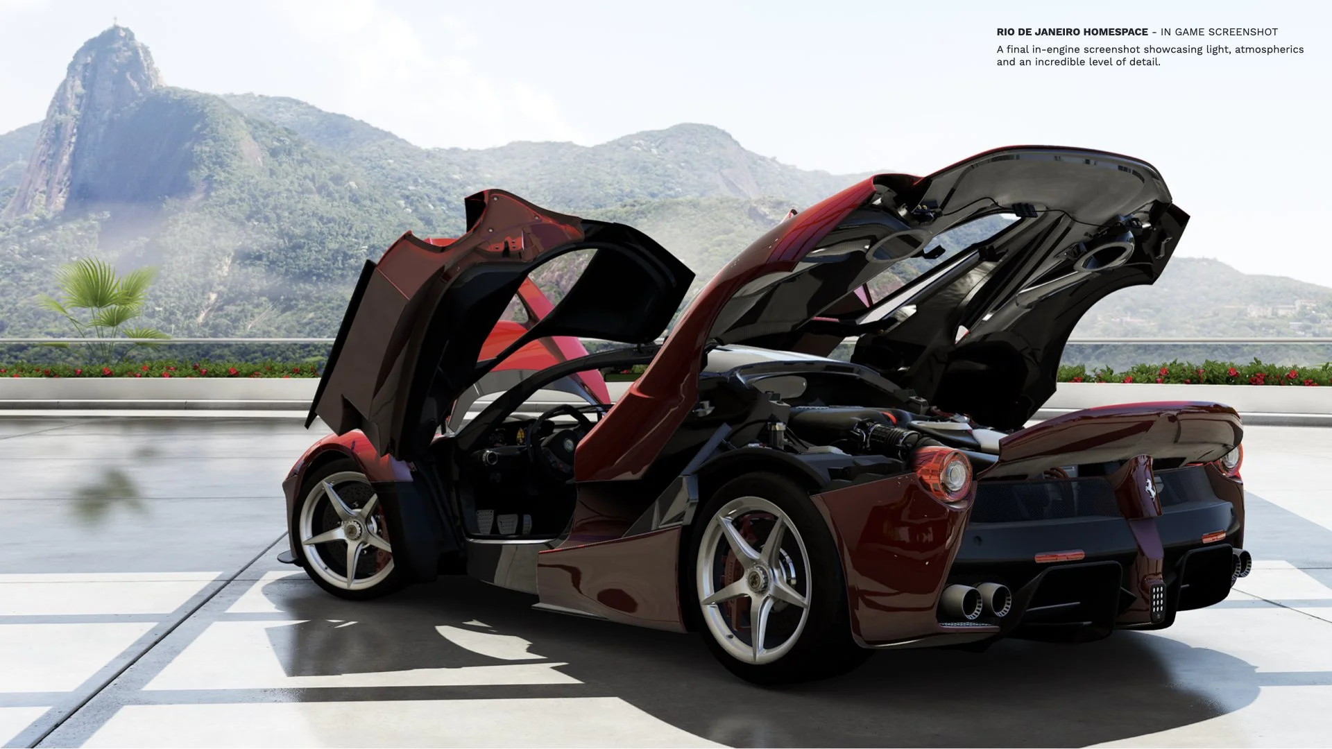 Red sports car with open gullwing doors parked on a rooftop with mountains and a blue sky in the background.