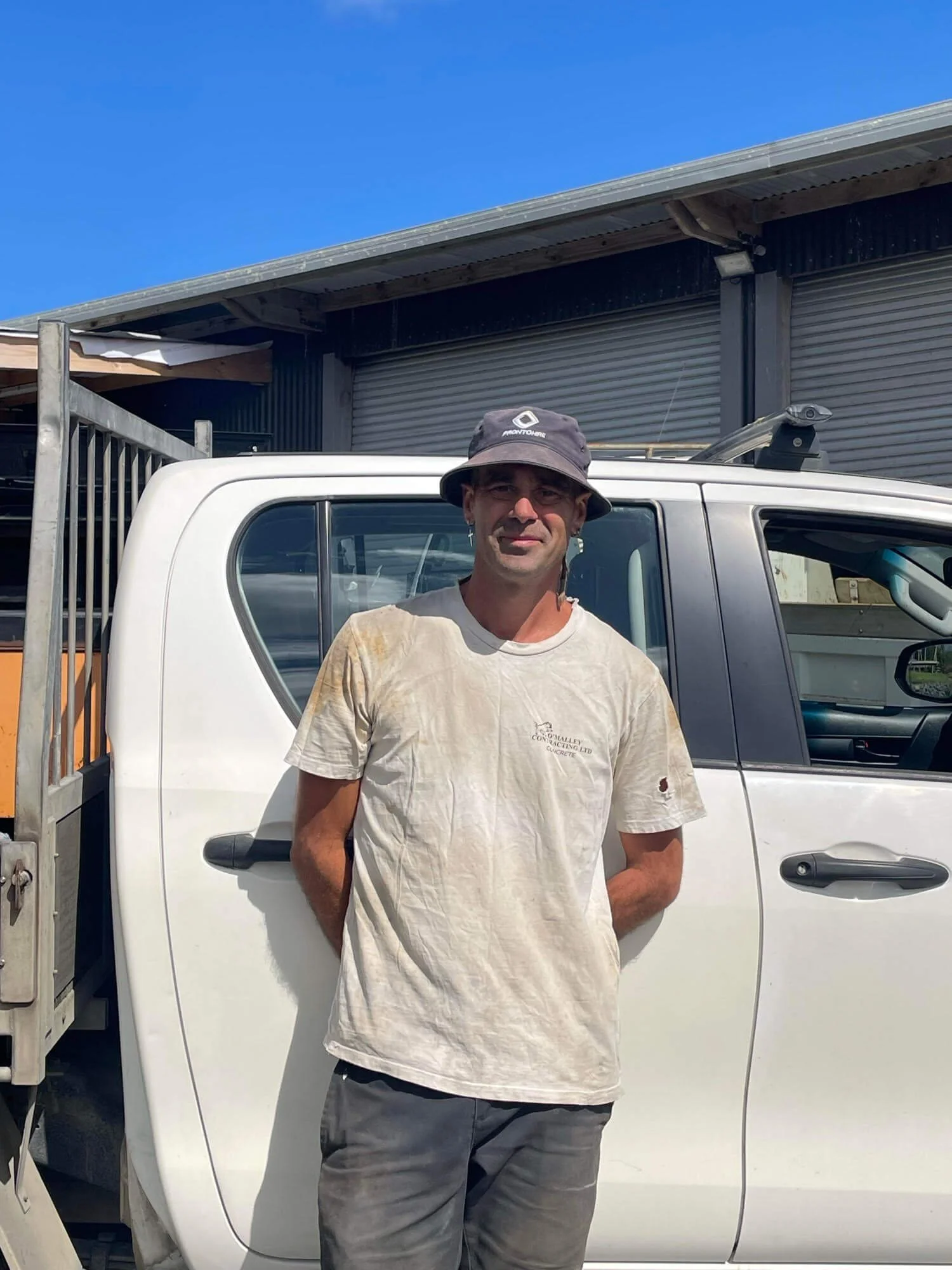 Peter O'Malley standing in front of a white pickup truck wearing a gray hat and white T-shirt.