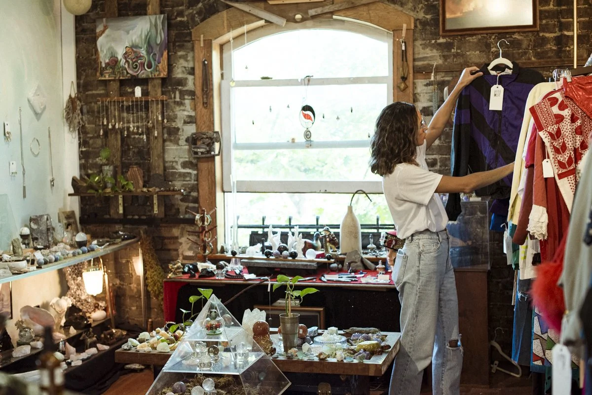 A woman looking through consignment clothes in a creative shop that also carries rock and gemstones.