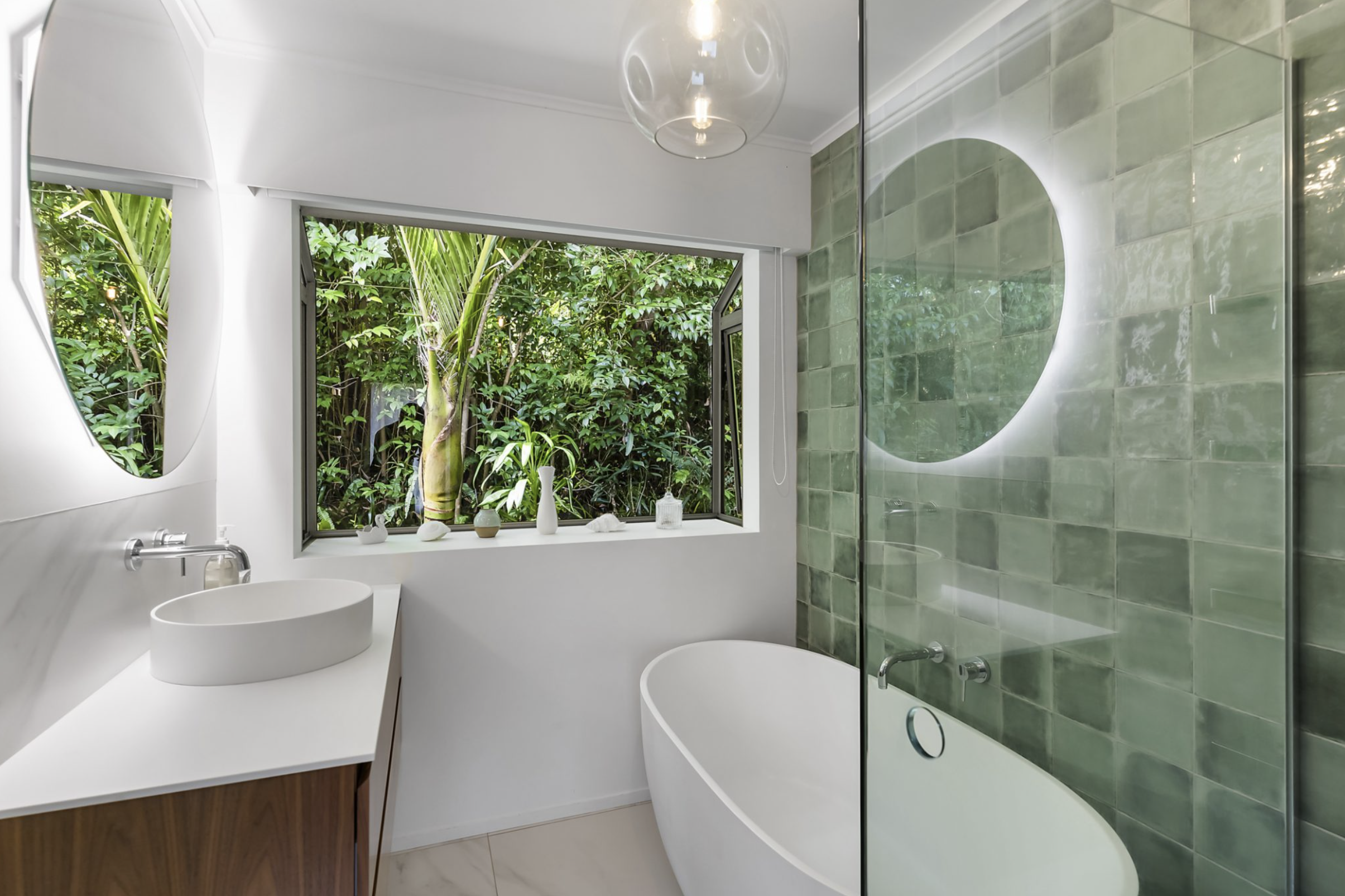 fresh and modern bathroom featuring elegant green tiles, a natural, calming ambiance