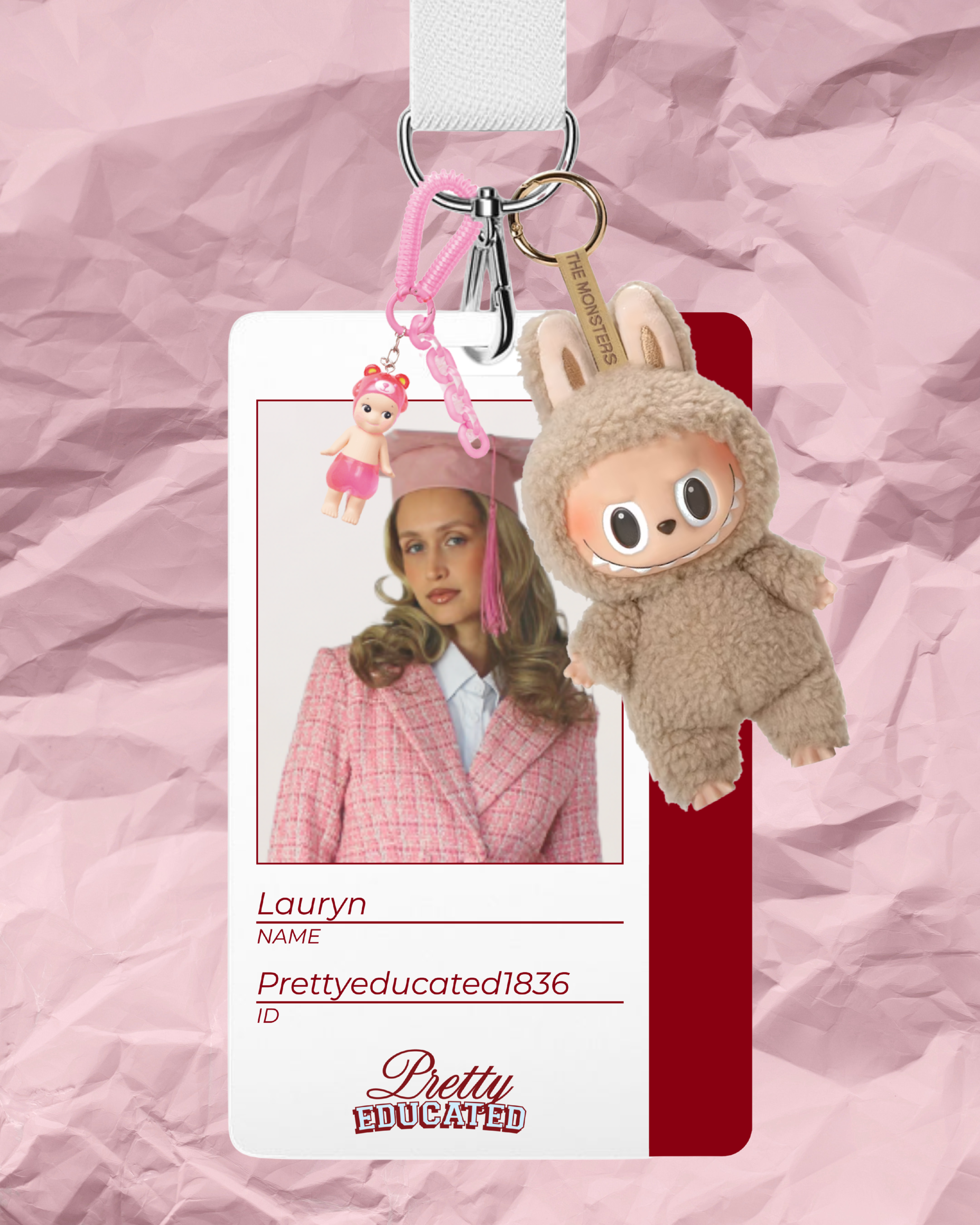 Close-up of a student ID card with the name Lauryn, featuring a photo of a woman with wavy blonde hair. The ID card is attached to a white lanyard and decorated with two plush keychains: one of a cute animal wearing a hoodie and another of a character in a bear costume hood. The background is pink crinkled paper.