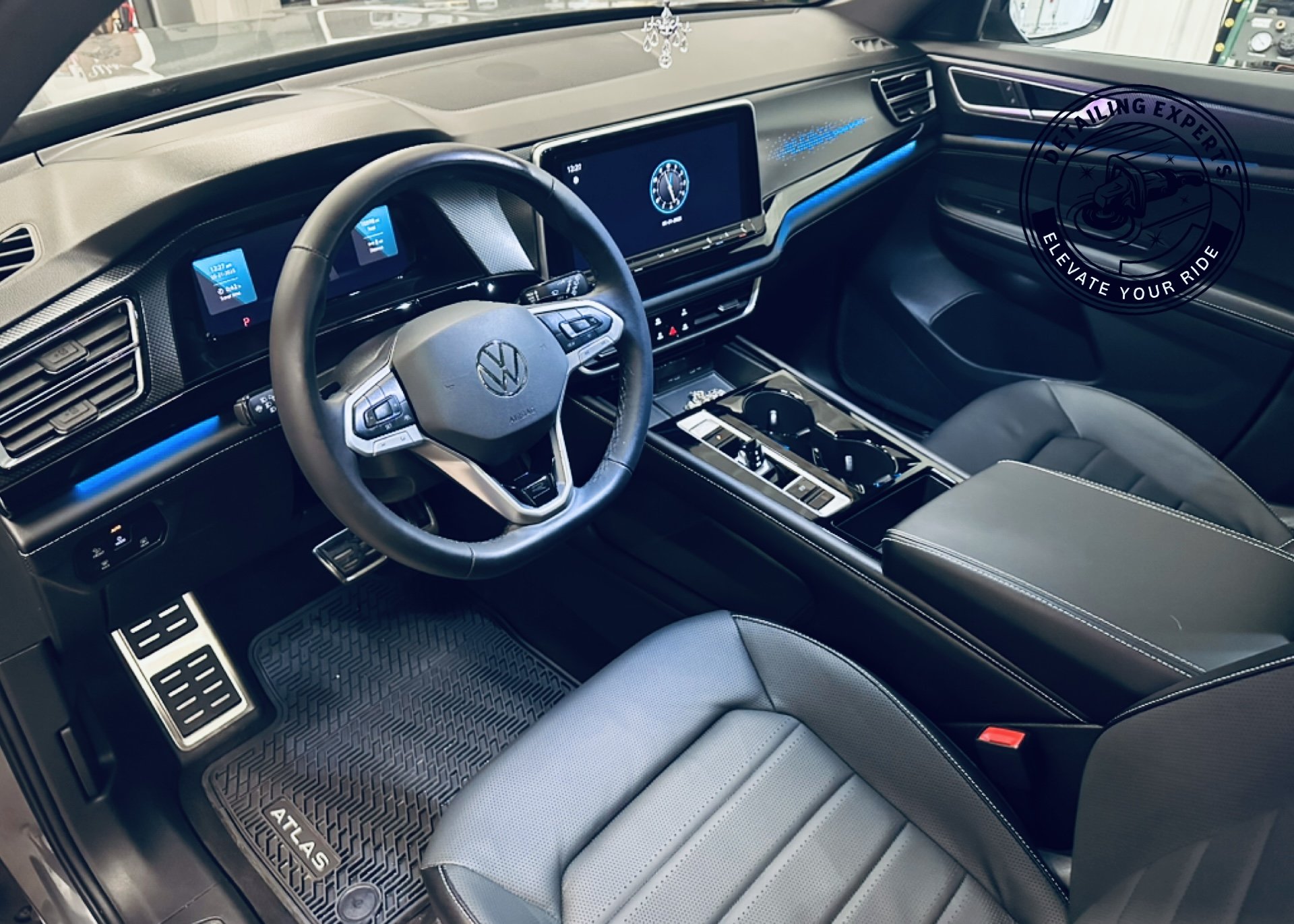 Interior of a Volkswagen vehicle, showing the dashboard with digital displays, steering wheel, center console with gear shifter and cup holders, and front passenger seat.
