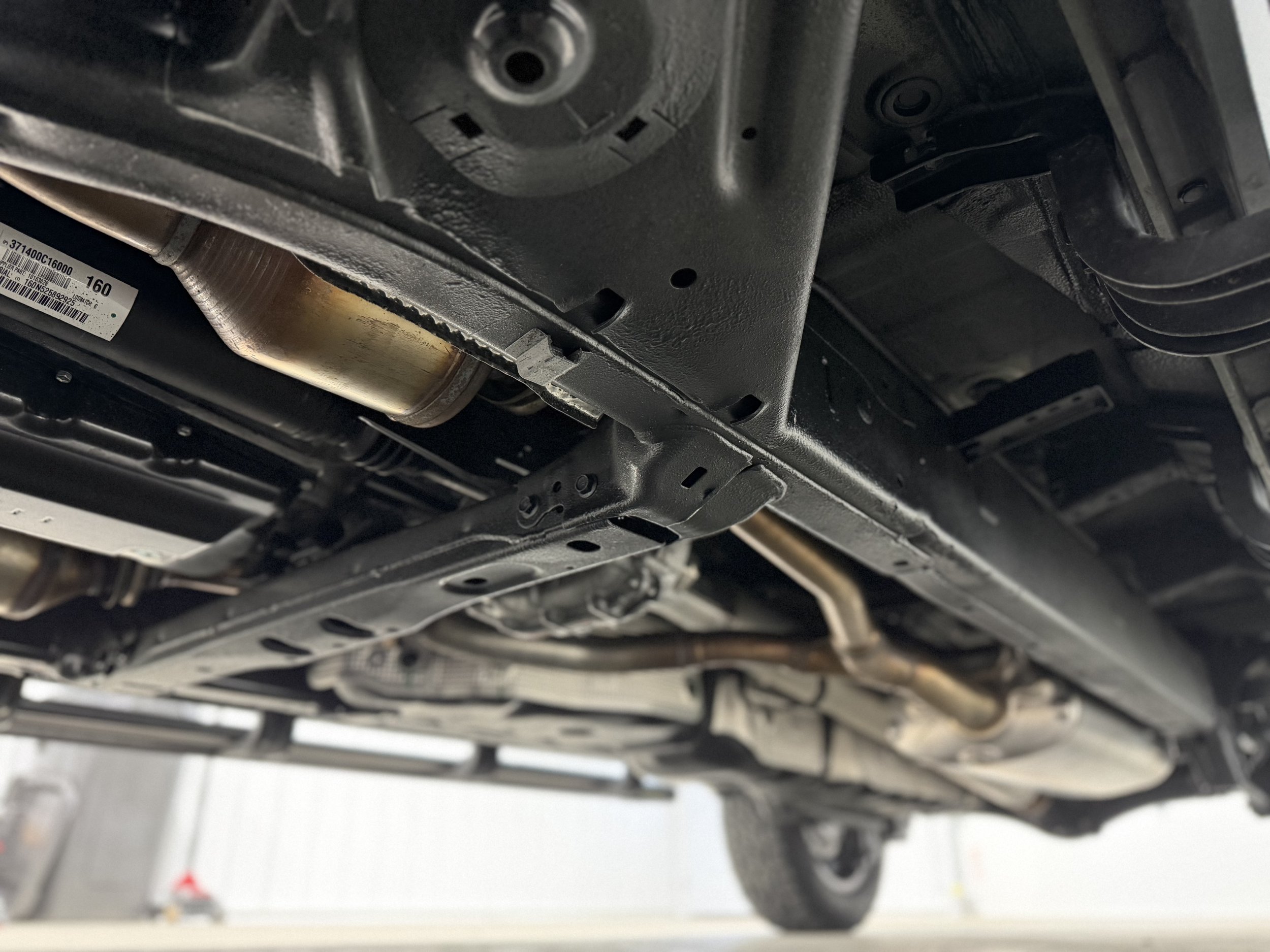 Underneath view of a car showing exhaust pipe, oil pan, and chassis components.