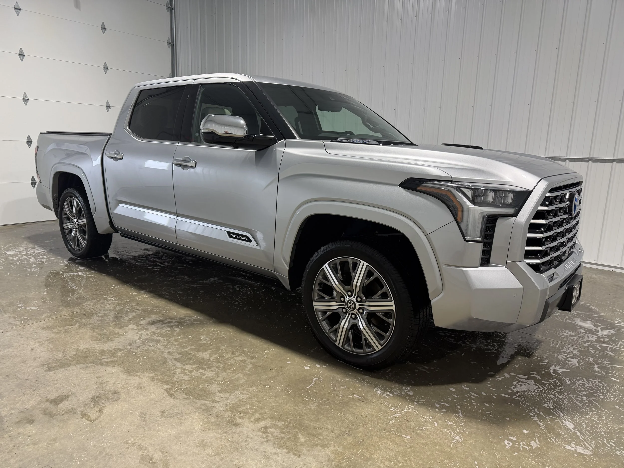 A silver Toyota Tundra pickup truck parked inside an indoor garage with white walls and a concrete floor.