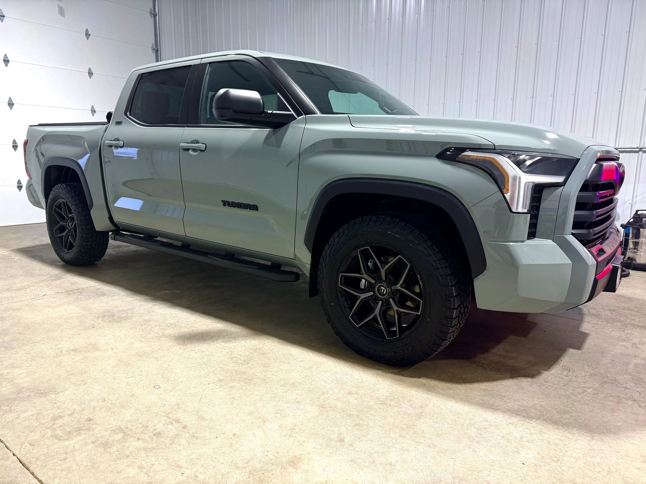 A mint green Toyota Tundra pickup truck parked inside a garage.