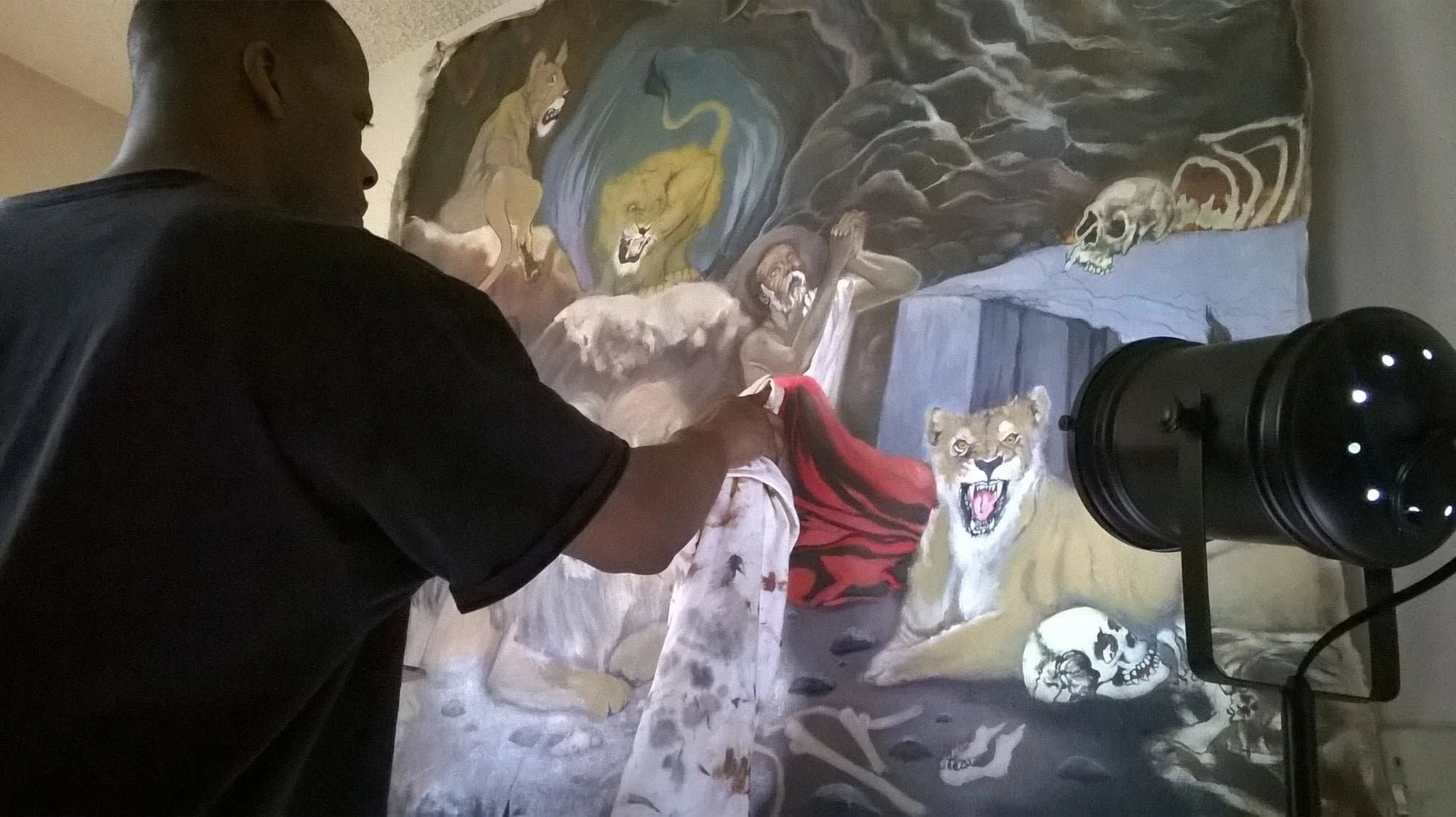 a picture of the artist Jerrick Jones painting a man praying with lions around the theme of Daniel in the Lions Den.
