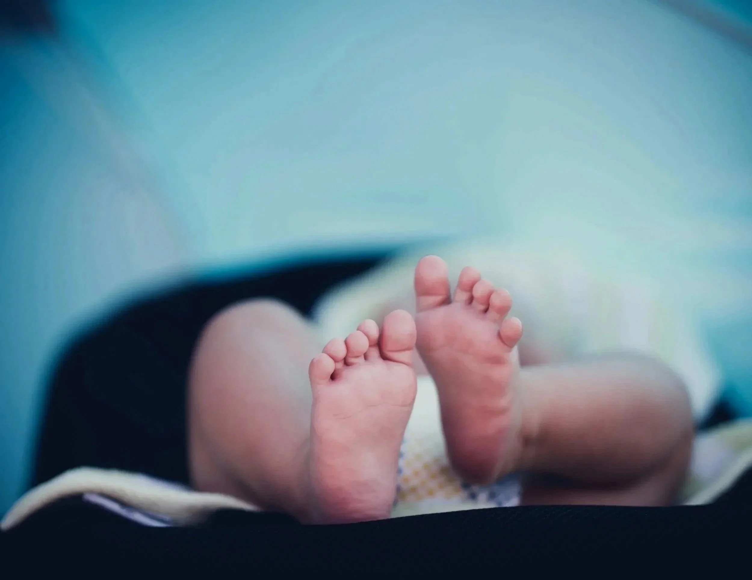 Close-up of a baby's feet with outstretched toes, lying on a blanket.
