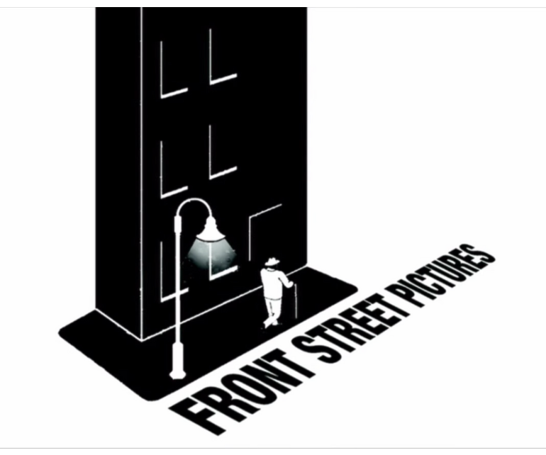 A black-and-white illustration of a person standing on a sidewalk at night, checking their phone or reading something under a street lamp, with the street name "Front Street Pictures" written in large, bold letters on the ground.