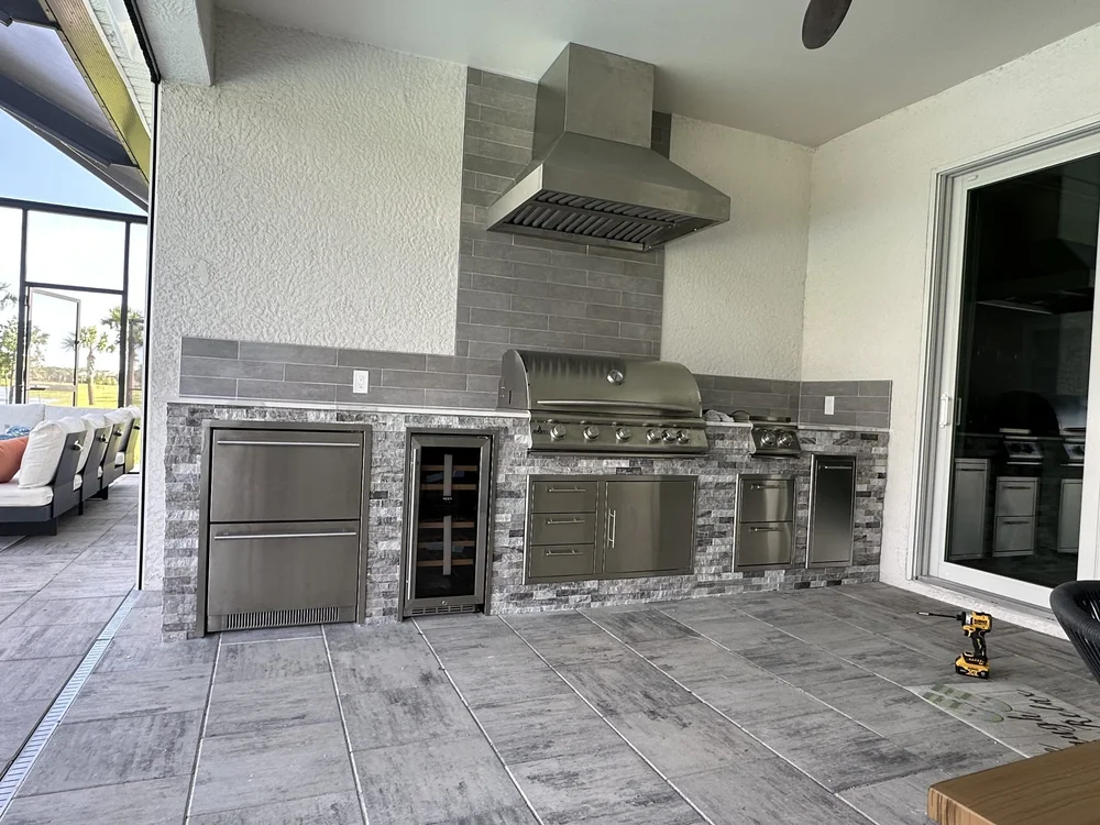 After: Custom outdoor kitchen with stacked stone, natural stone counters and vented hood - Southwest Florida