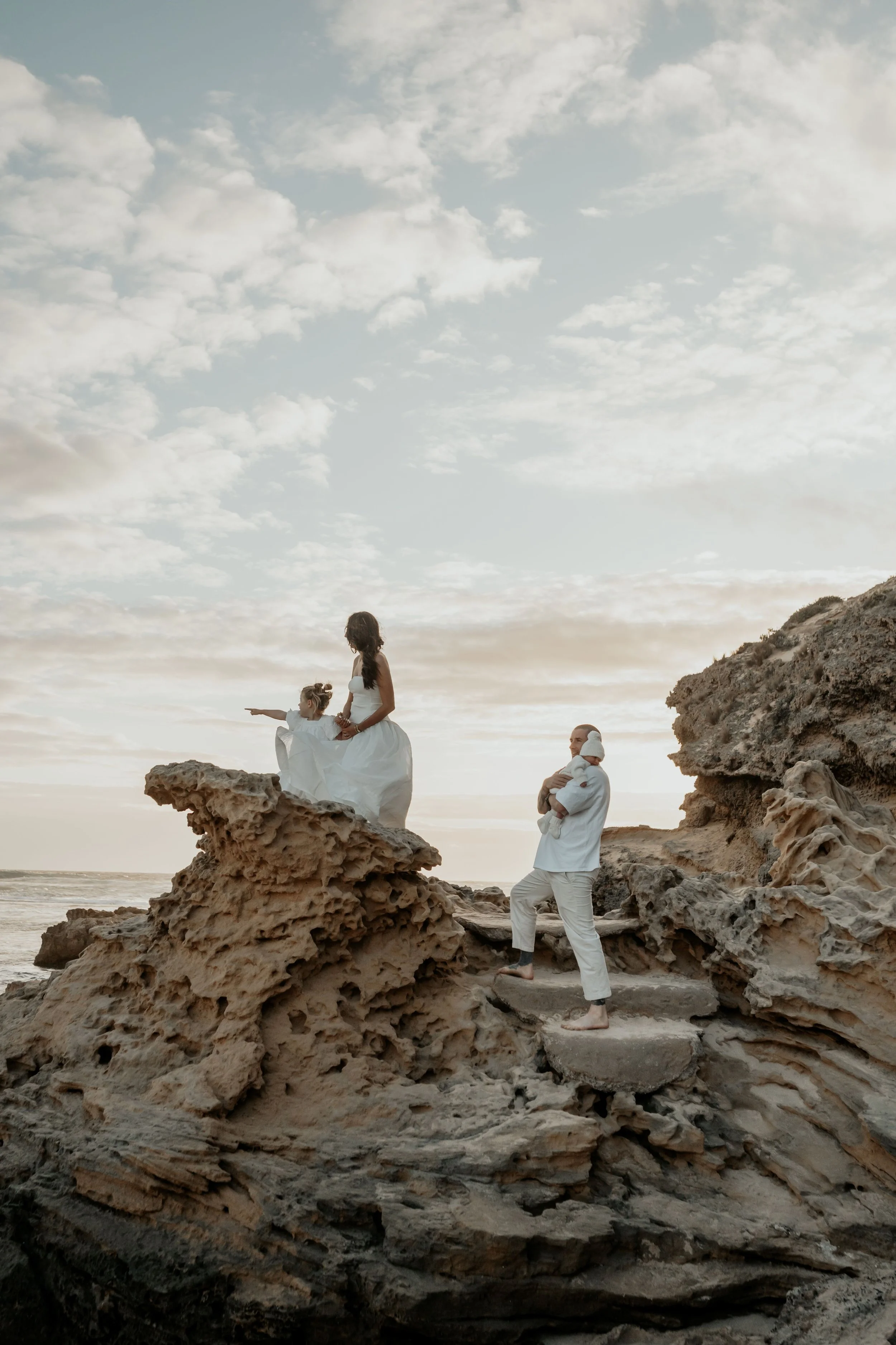 A famiy standing on a rock formation looking at the view of Sorrento Back Beach