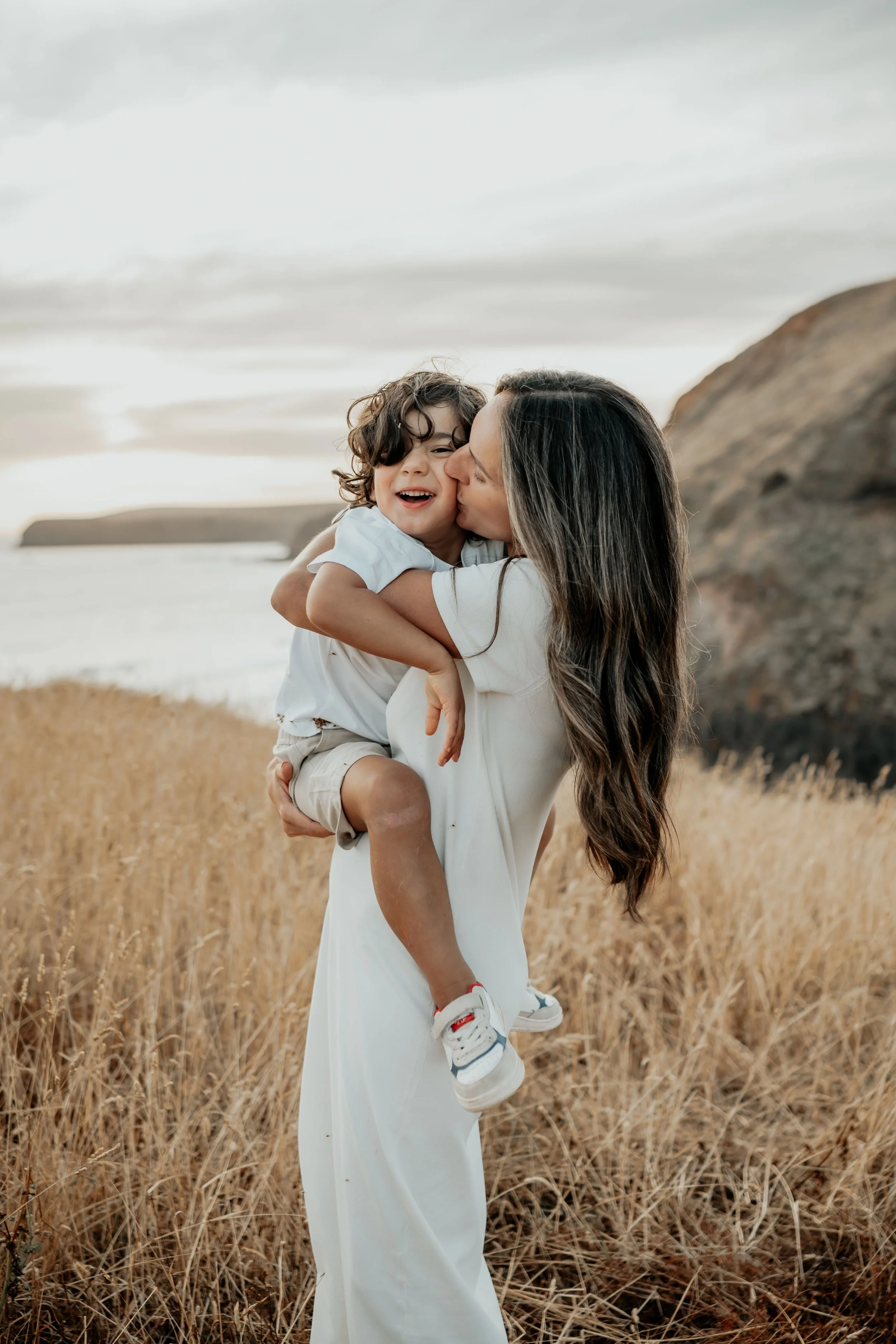 A mother holds her son closely and kisses him on the cheek