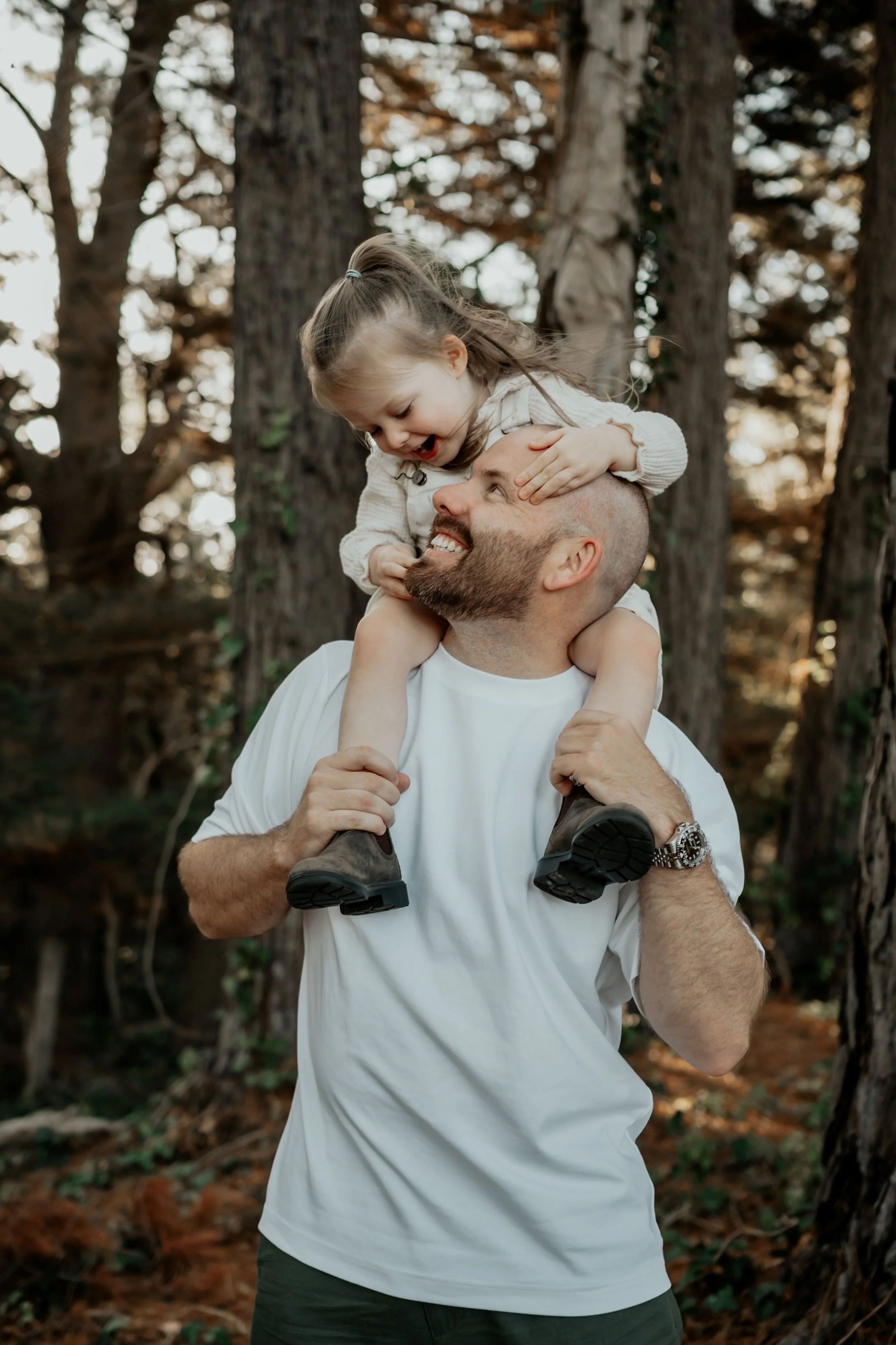 A father giving his daughter a shoulder ride while they look at each other and laugh together